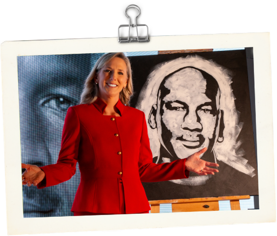Dr. Heather Hodges in red blazer smiling and presenting in front of an audience with a black and white portrait of Michael Jordan behind her.