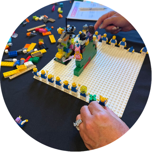 Lego creation on a black table with a person's hand and some scattered Lego pieces.
