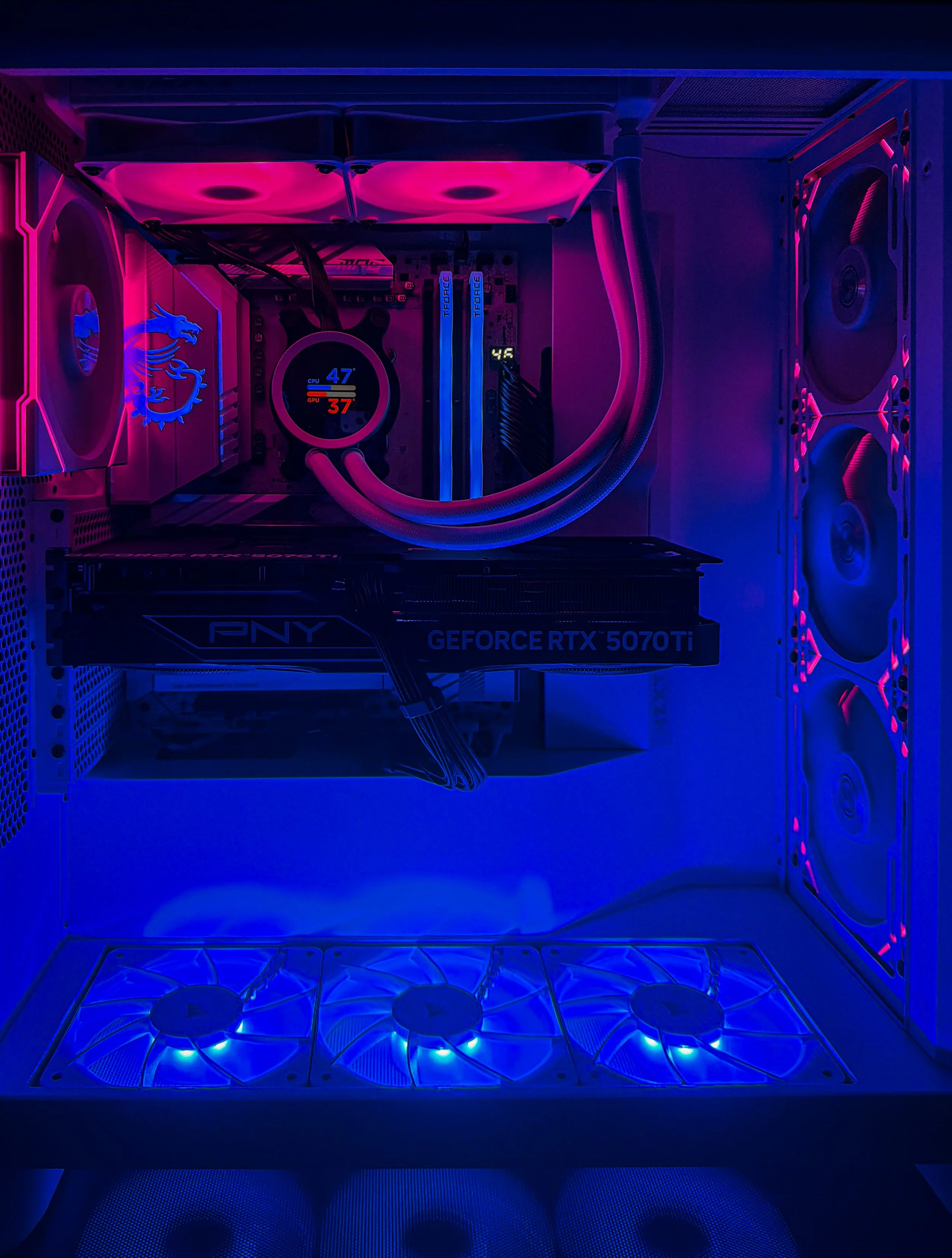 Close-up of the interior of a gaming computer with RGB lighting, showing cooling fans, a CPU cooler, RAM modules, a graphics card, and illuminated components.