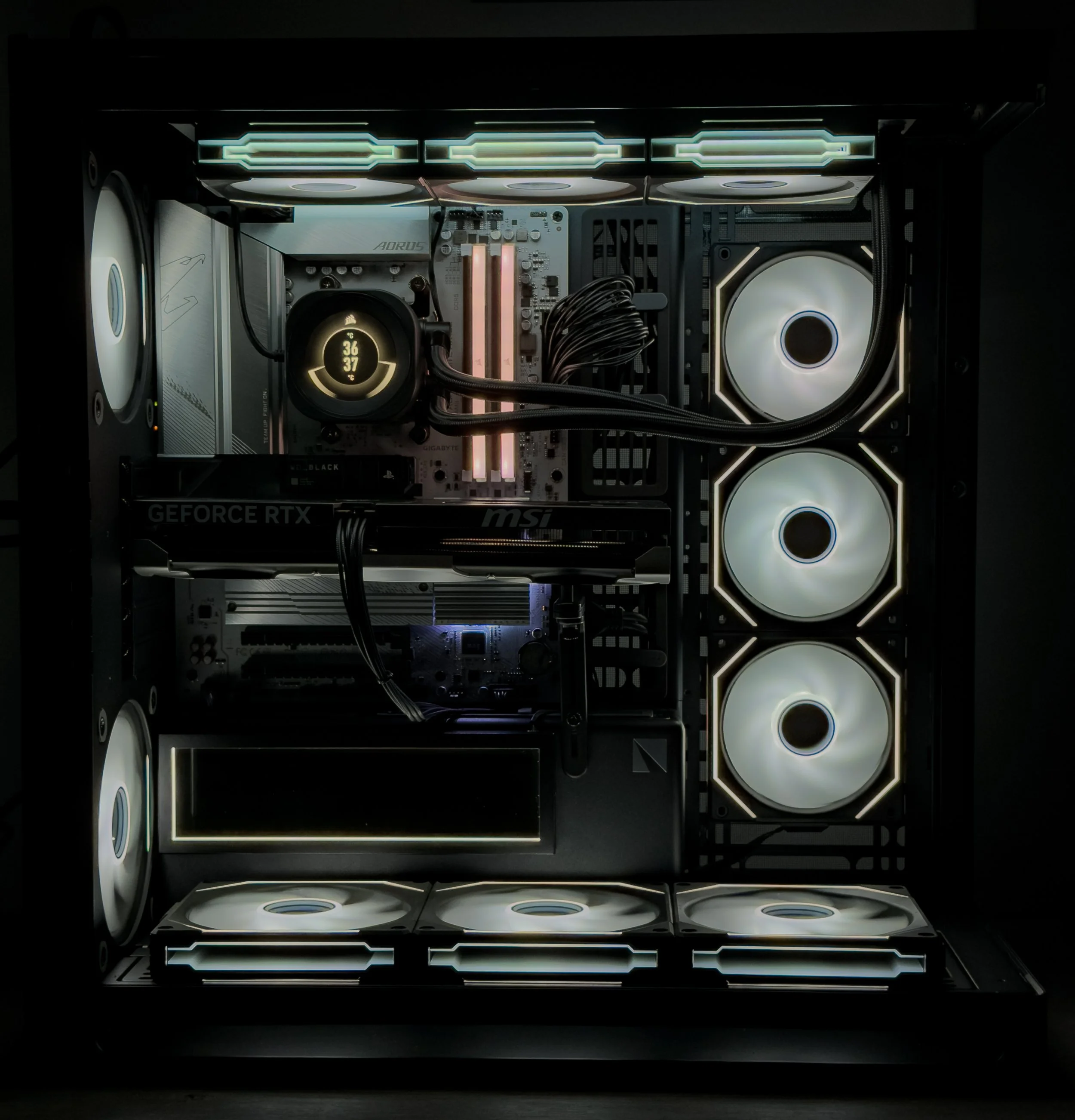 Inside of a computer case showing cooling fans with white lighting, a motherboard, a CPU cooler, RAM sticks, and NVIDIA GeForce RTX graphics card.