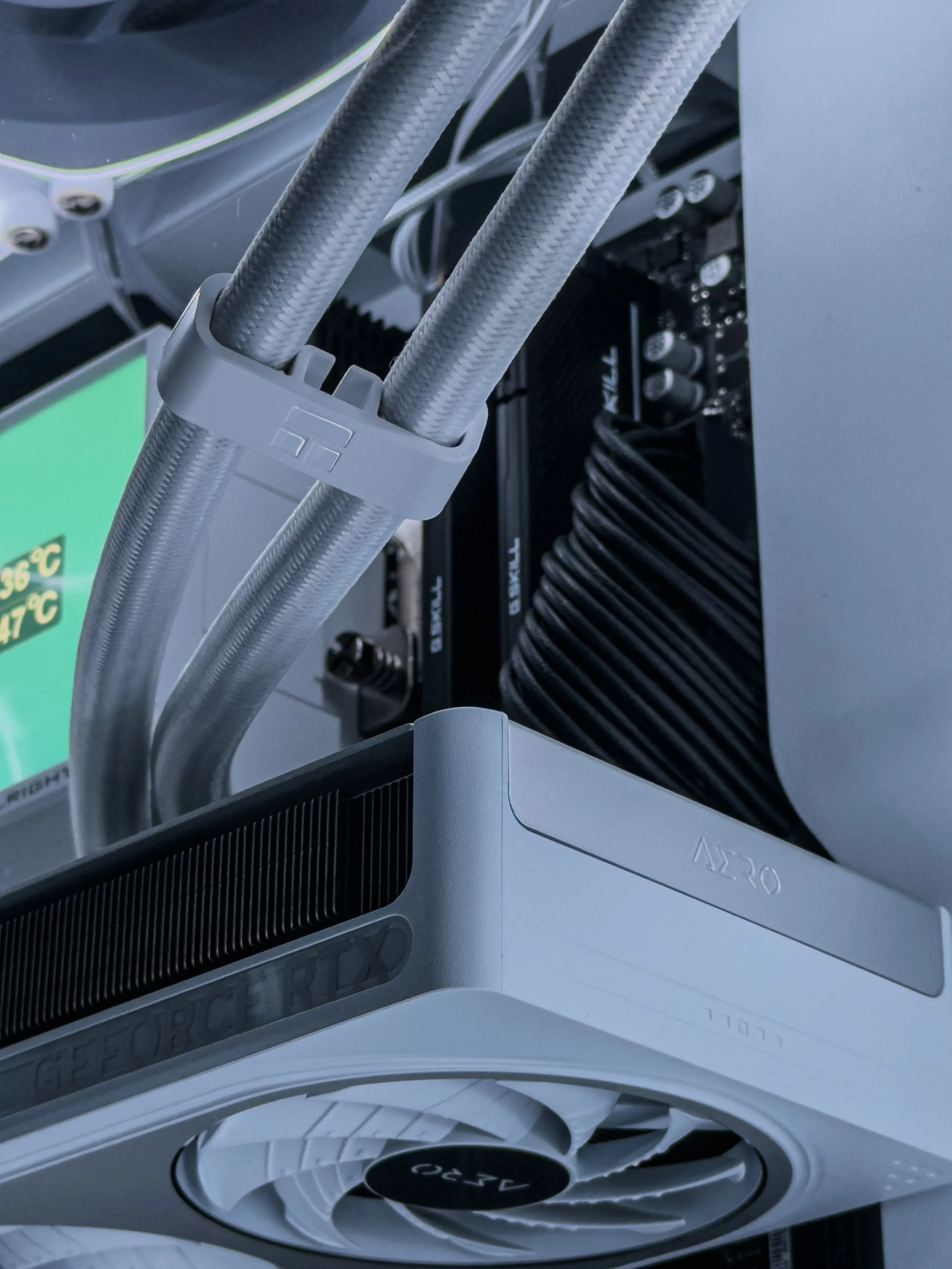 Close-up of a computer graphics card with white and silver cooling pipes and black heatsink.