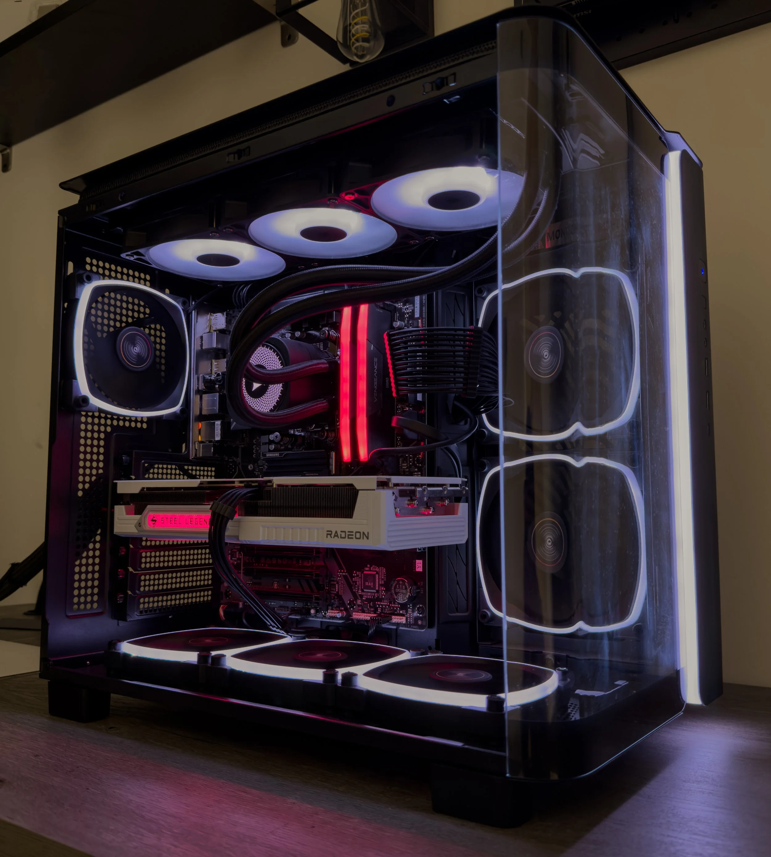 A custom-built gaming computer with a transparent side panel, illuminated cooling fans, RGB lighting, and various hardware components visible inside.