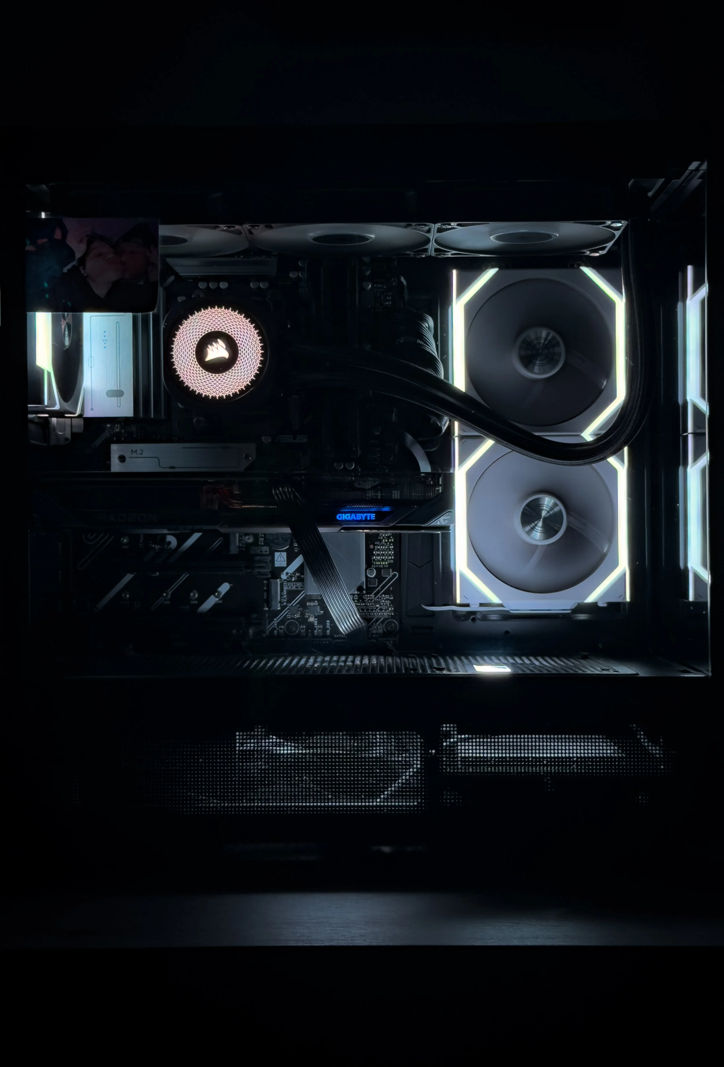 Inside view of a gaming or high-performance computer with illuminated components, including cooling fans, a CPU cooler with a flame logo, and RGB lighting accents.