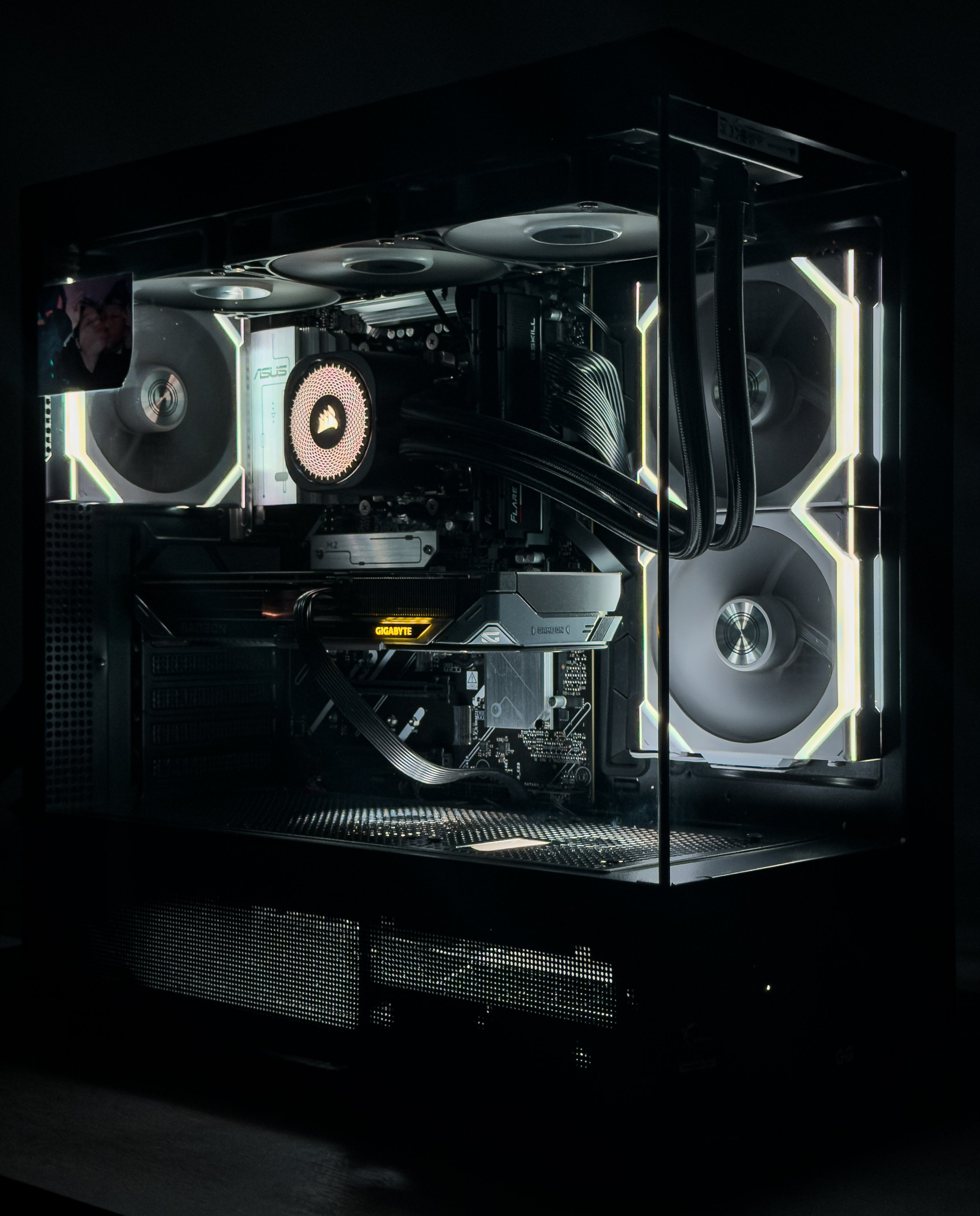 Inside a high-end gaming or custom computer case with illuminated components, including fans, a graphics card, and cooling systems, visible through a transparent side panel.