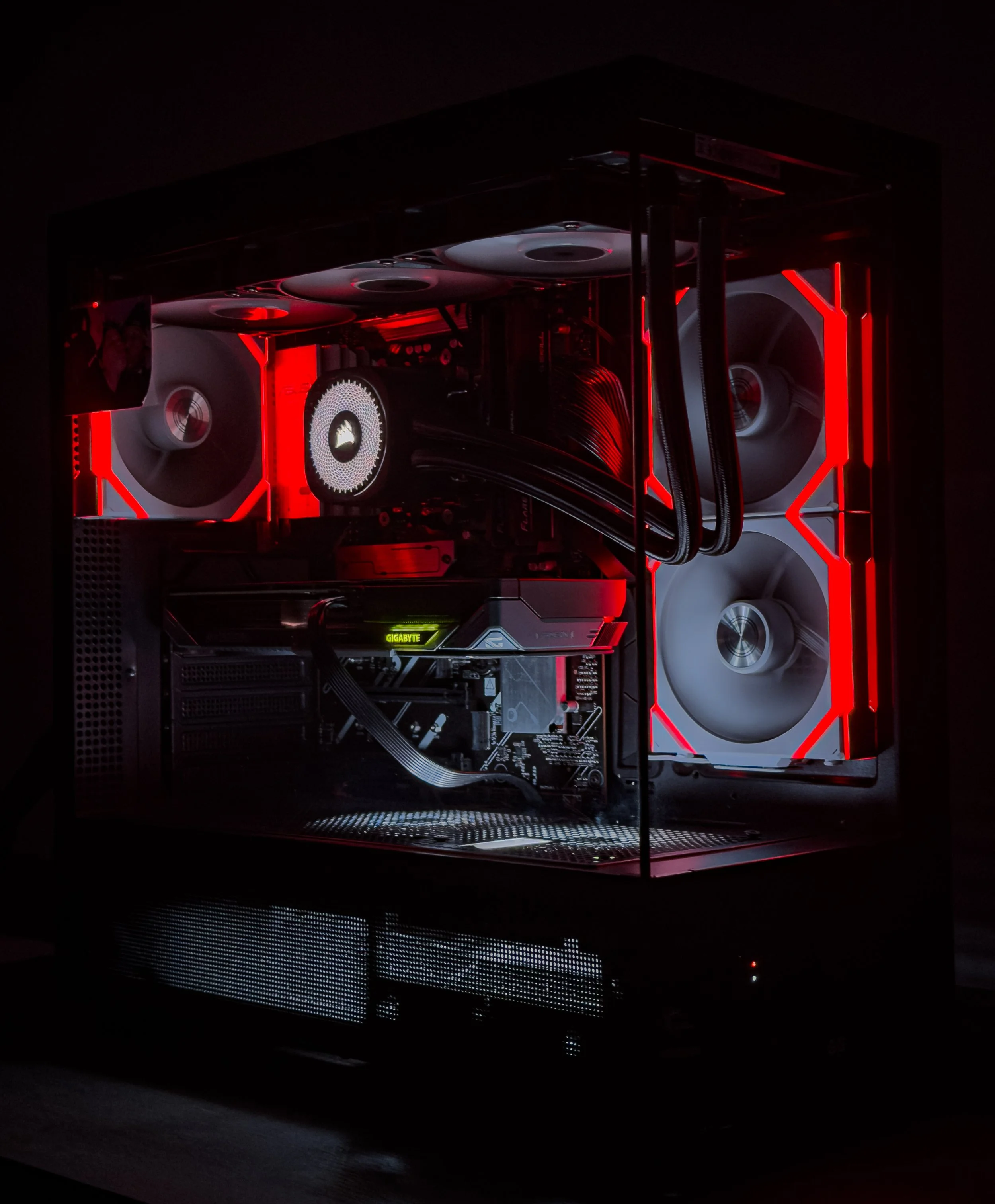 A modern gaming computer with illuminated fans, graphics card, and internal components visible through a glass case with red accents.