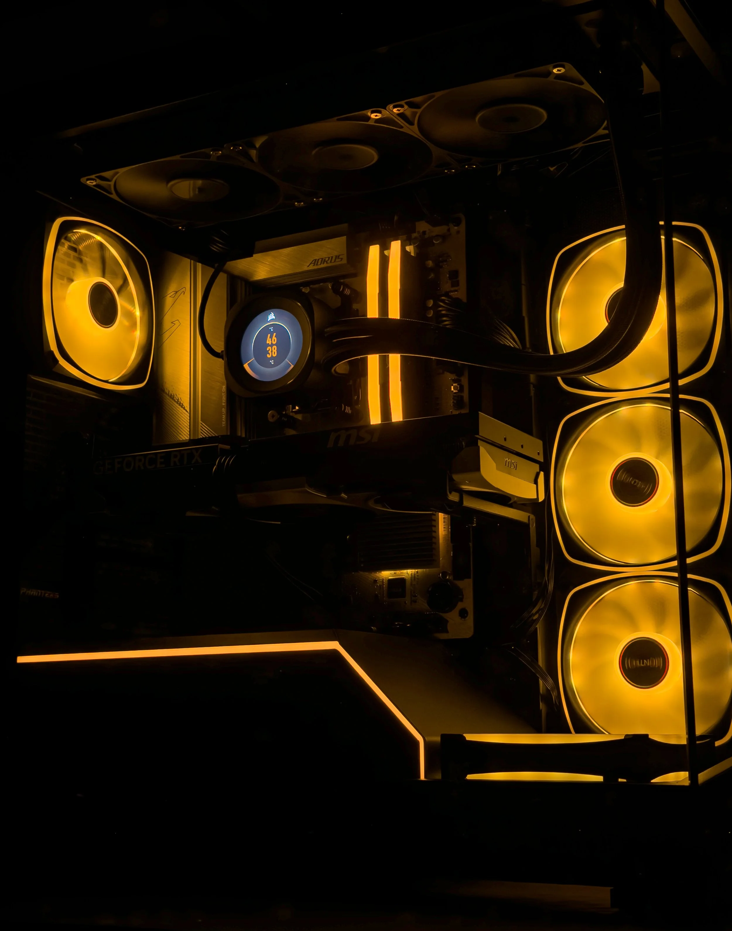 Close-up of a gaming computer with yellow LED lights, three large cooling fans, a digital temperature display, and internal components visible.