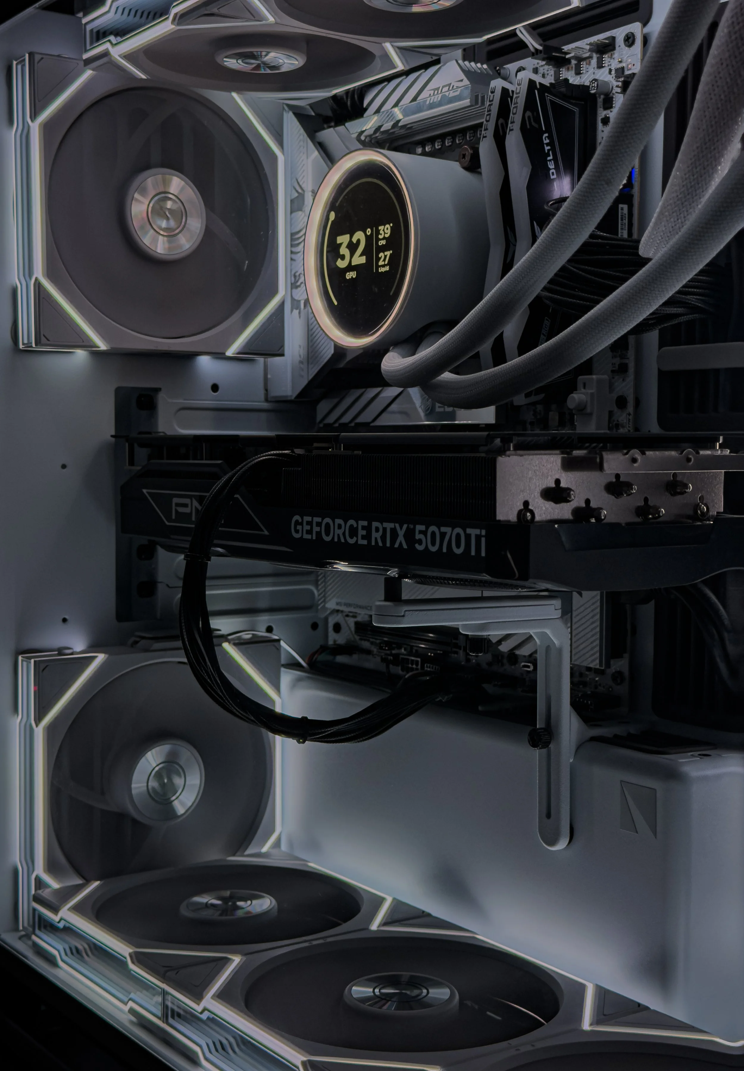 Interior view of a gaming or computer setup featuring multiple large speakers, a graphics card labeled 'GEFORCE RTX 5070 Ti', and a monitor displaying system temperature and performance metrics, with a cool, futuristic design.