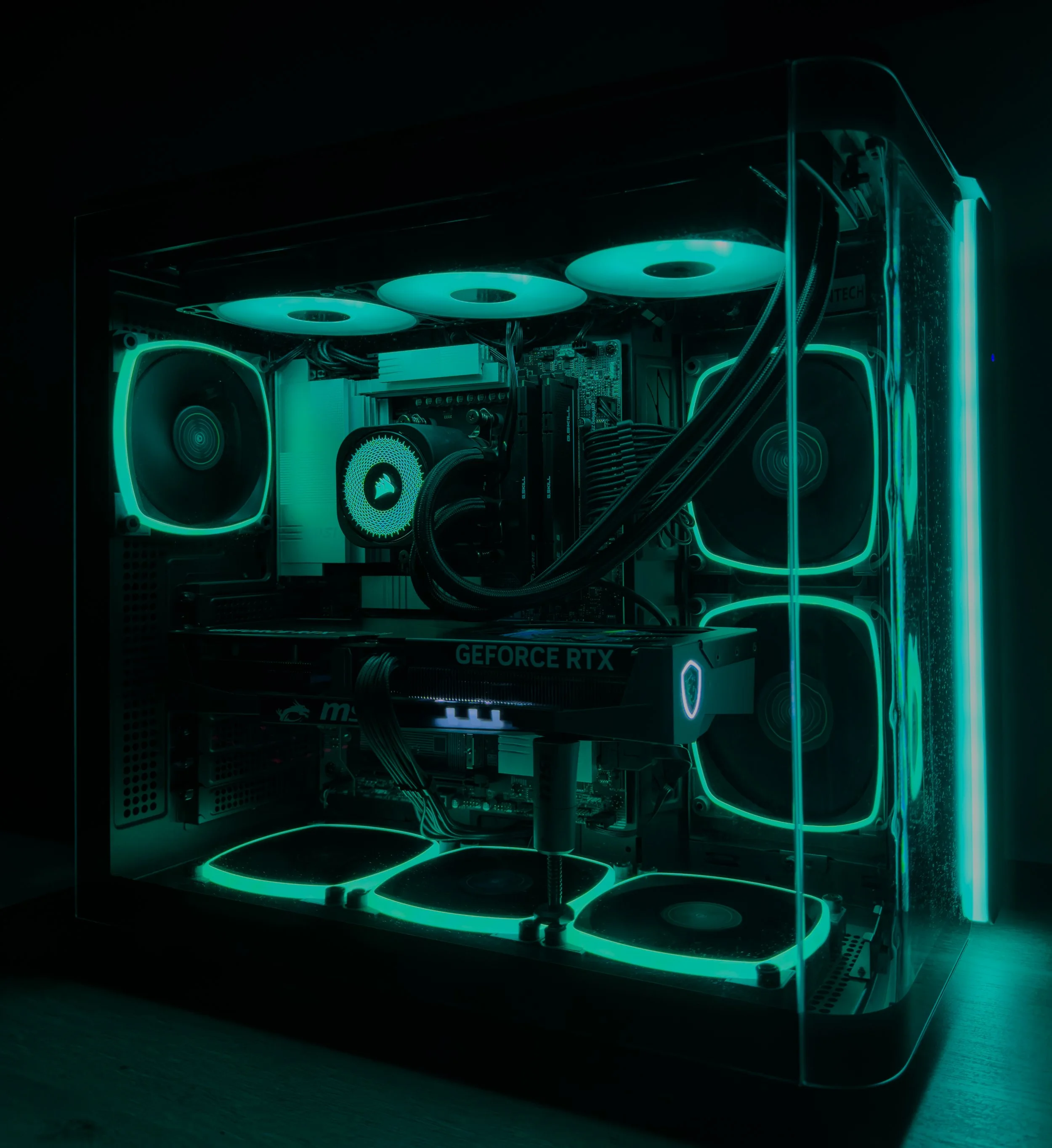 A custom-built gaming computer with glowing neon lights inside a transparent case, showcasing cooling fans and a graphics card labeled 'GEFORCE RTX'.