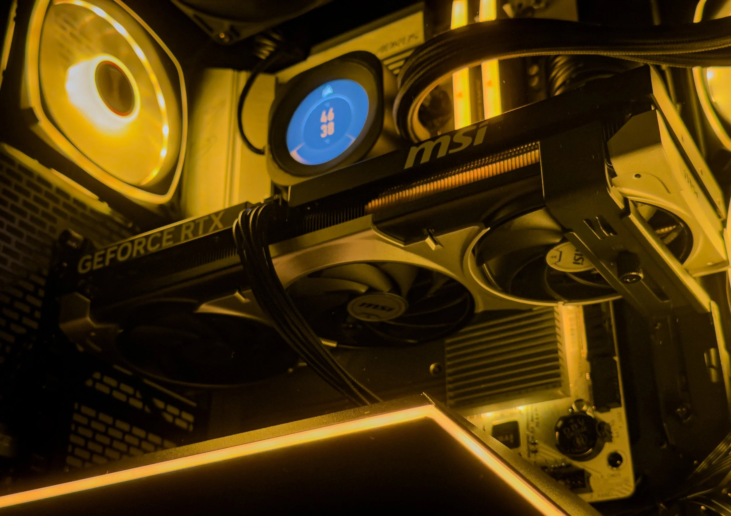 Close-up photo of a computer graphics card inside a computer case with glowing yellow and blue lights.
