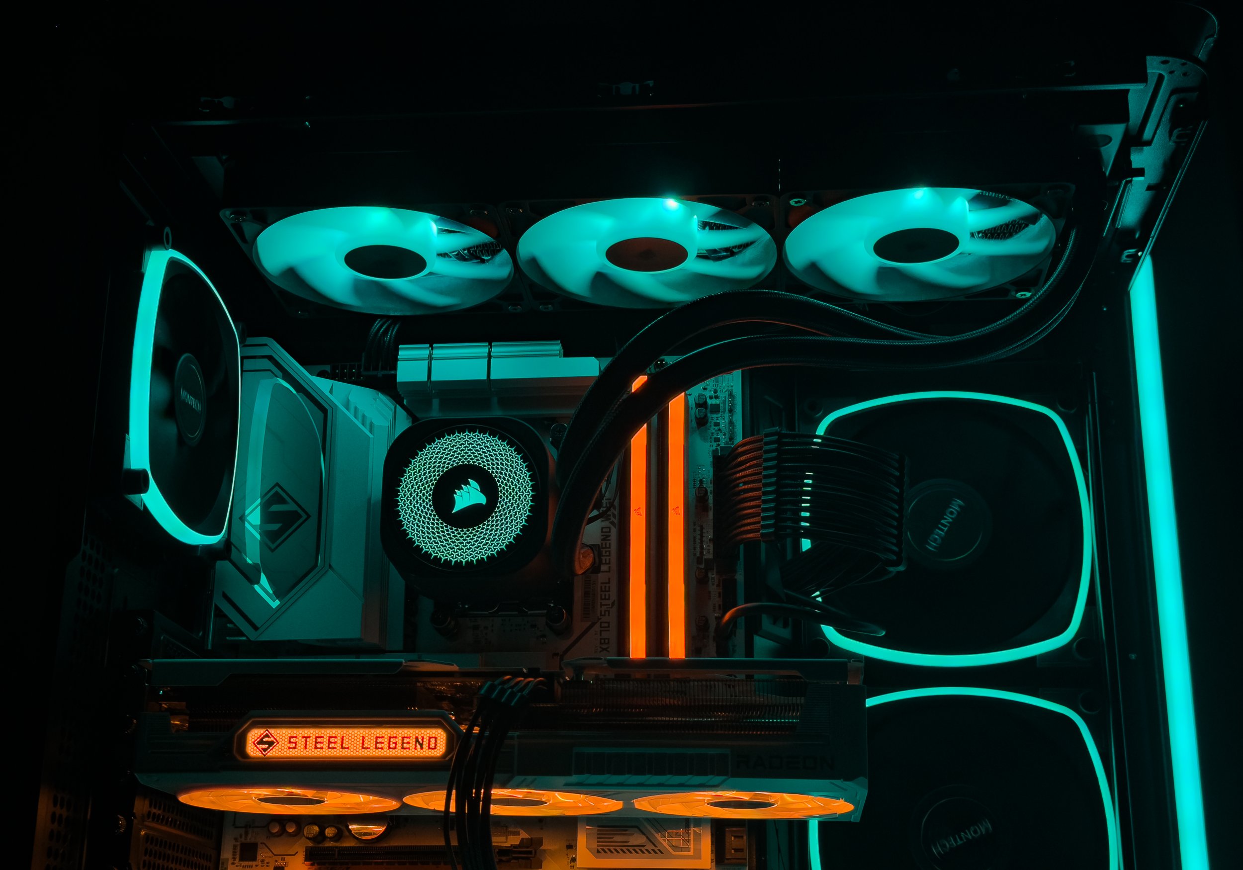 Interior of a gaming or high-performance computer with three illuminated cooling fans, RGB lighting, and various hardware components visible.