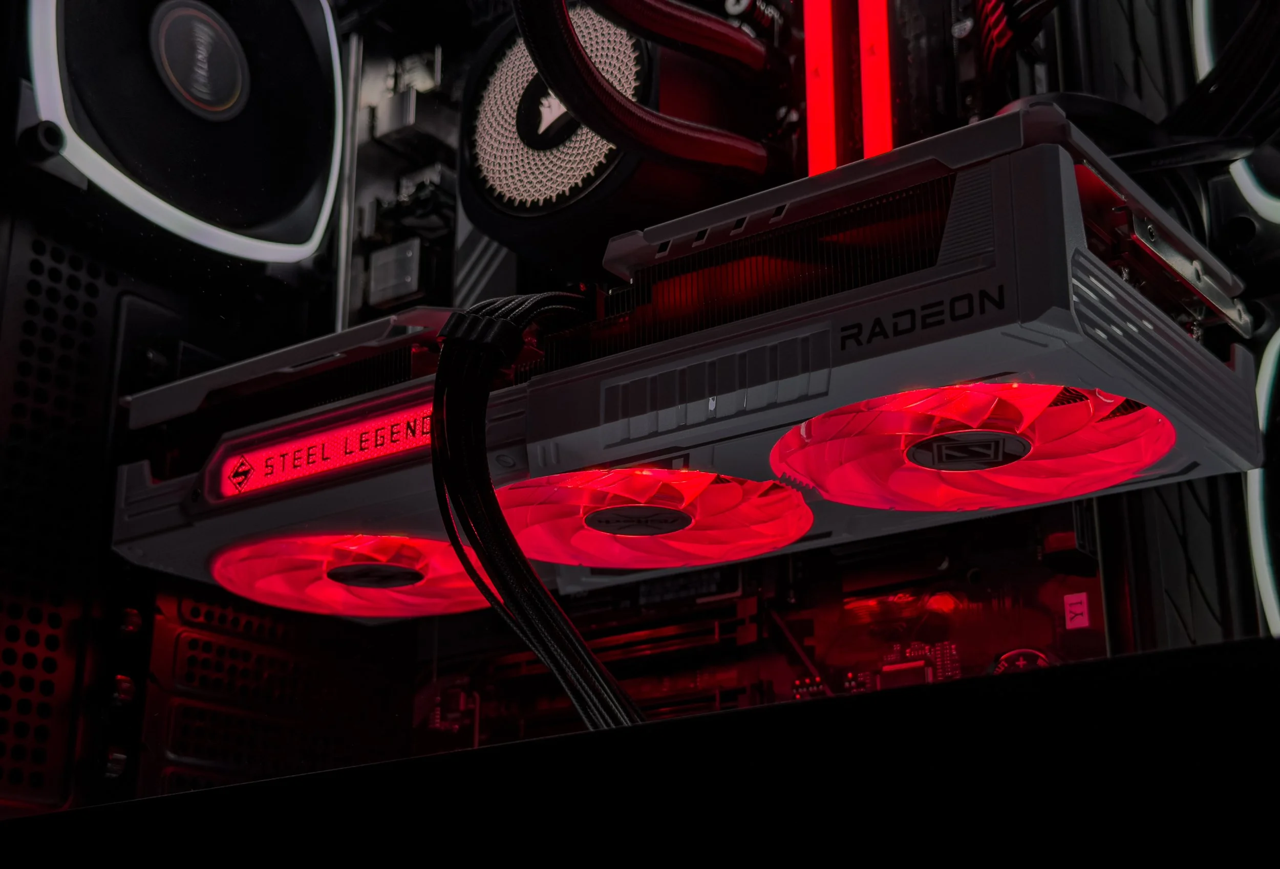 Close-up of a gaming computer's interior with a graphics card displaying red LED lighting and the words 'Steel Legend' and 'Radeon' visible.