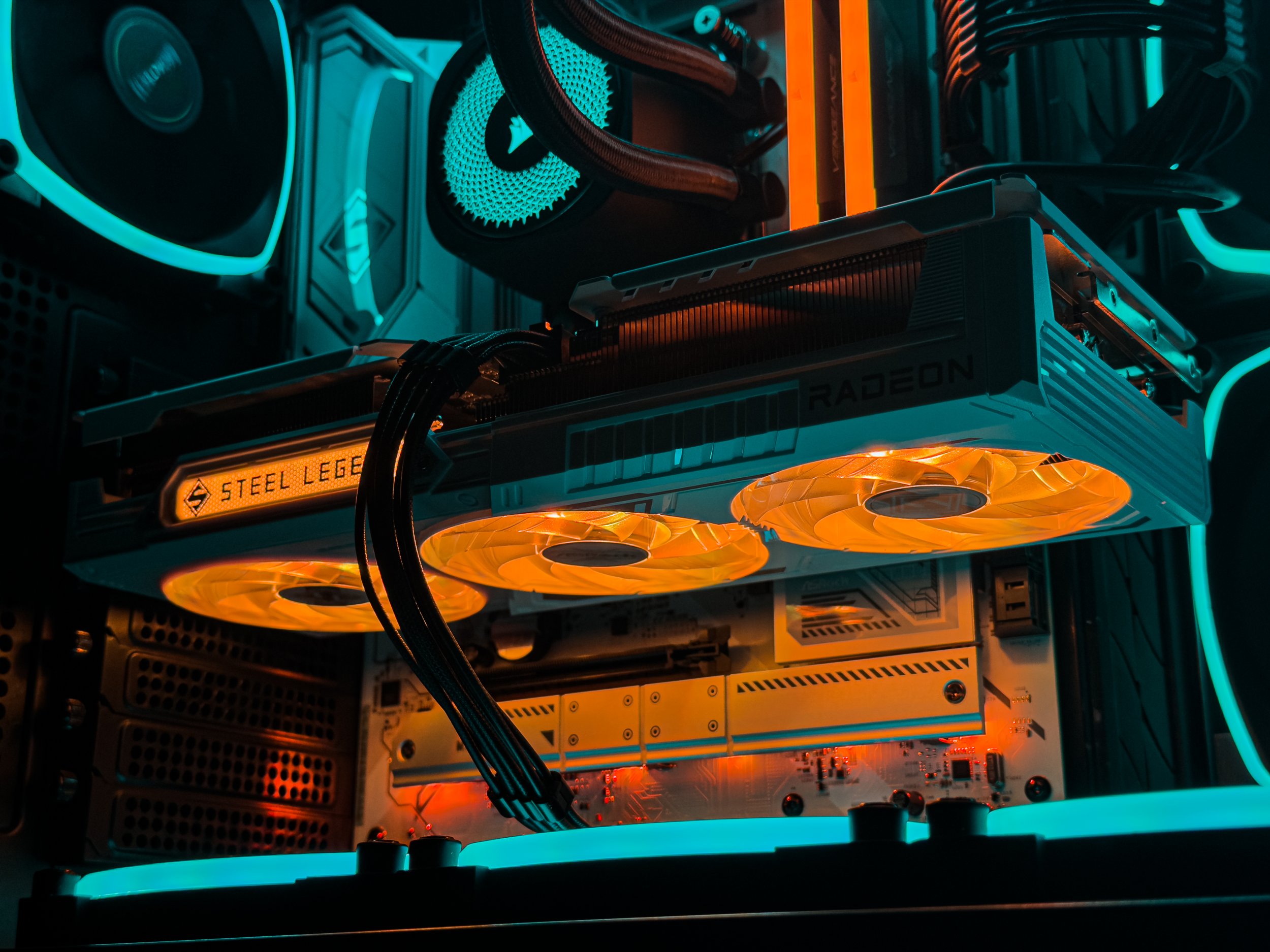 Close-up of a computer graphics card with glowing orange fans and illuminated cooling components inside a gaming or high-performance PC.