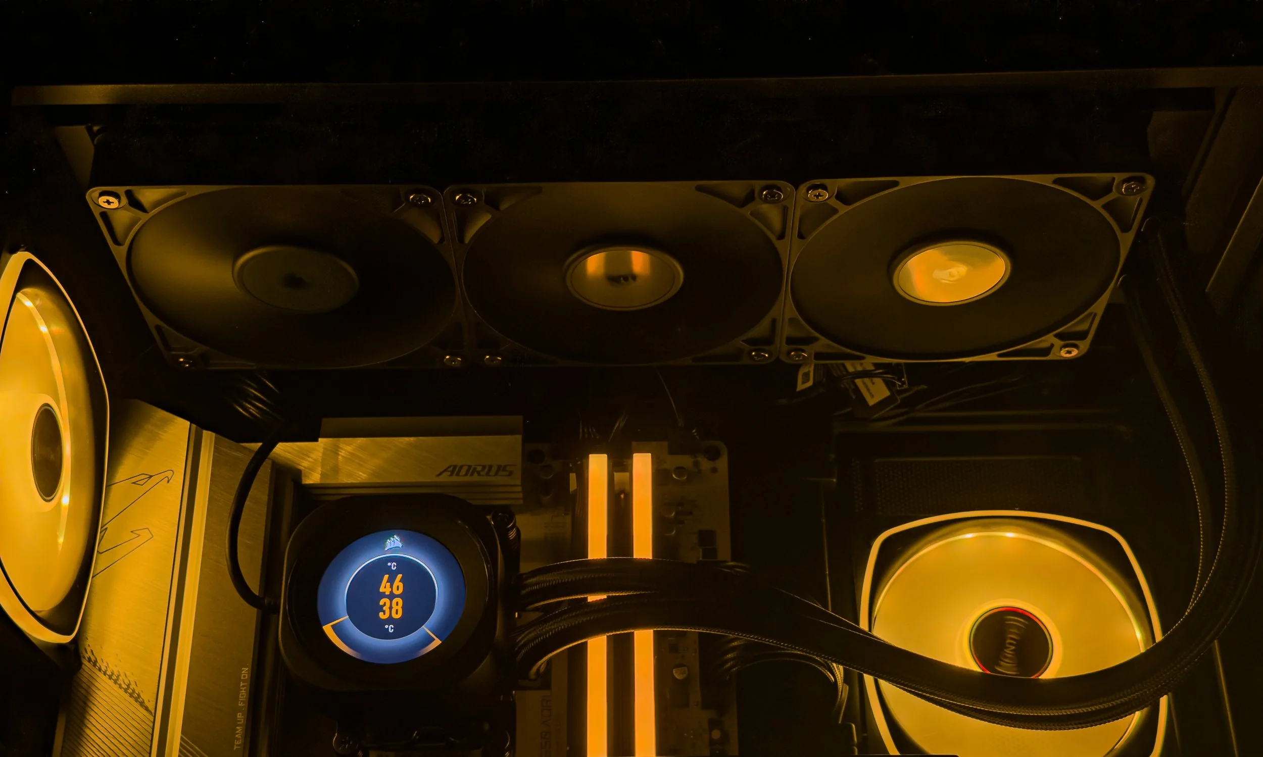 Close-up of a computer processor with three yellow cooling fans mounted above it, inside a computer case with visible cables and a circular display showing temperature readings.