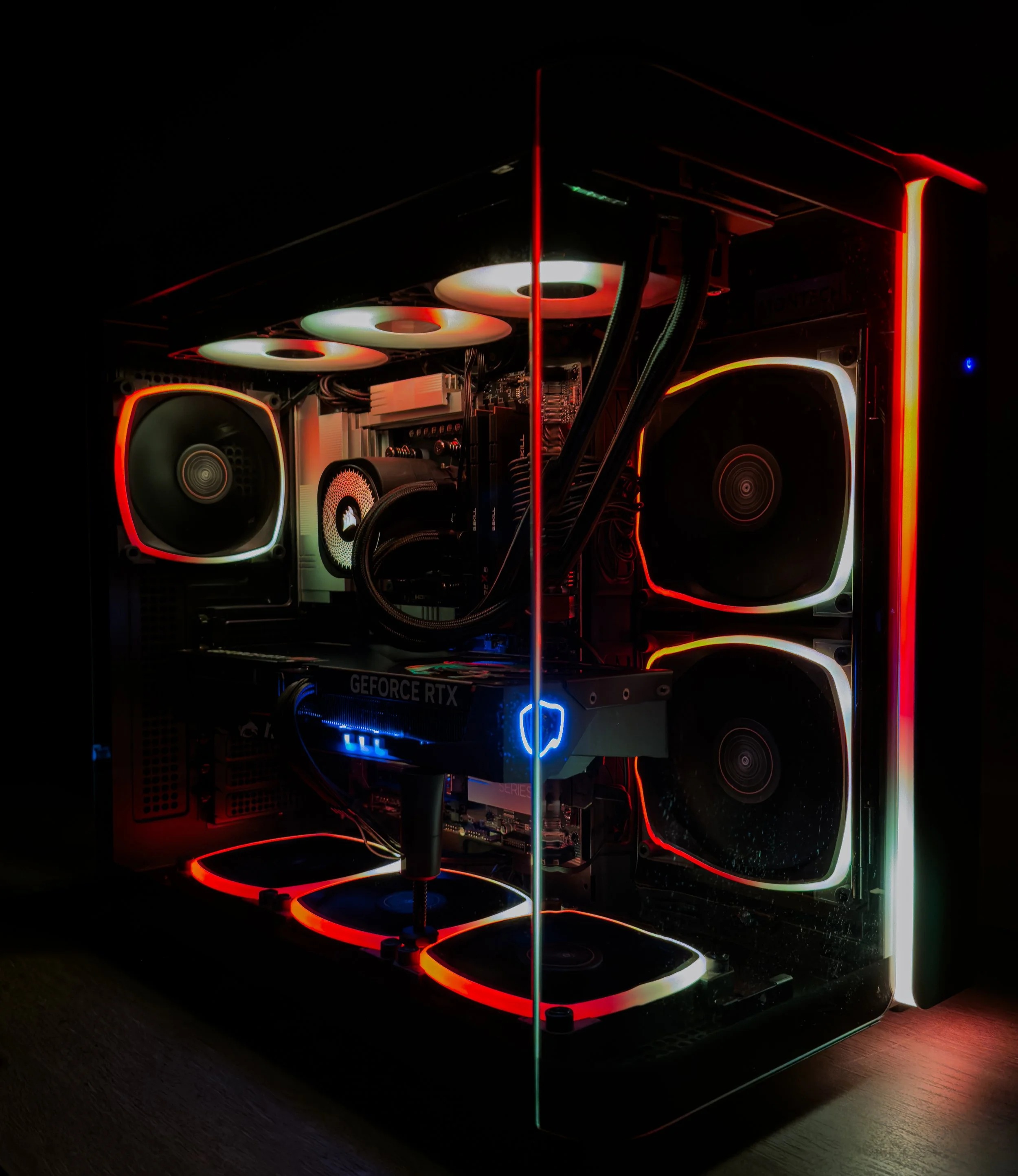 A computer build with illuminated RGB cooling fans, neon-colored LED strips, and a graphics card, all set in a dark room for a vibrant gaming or high-performance computer setup.