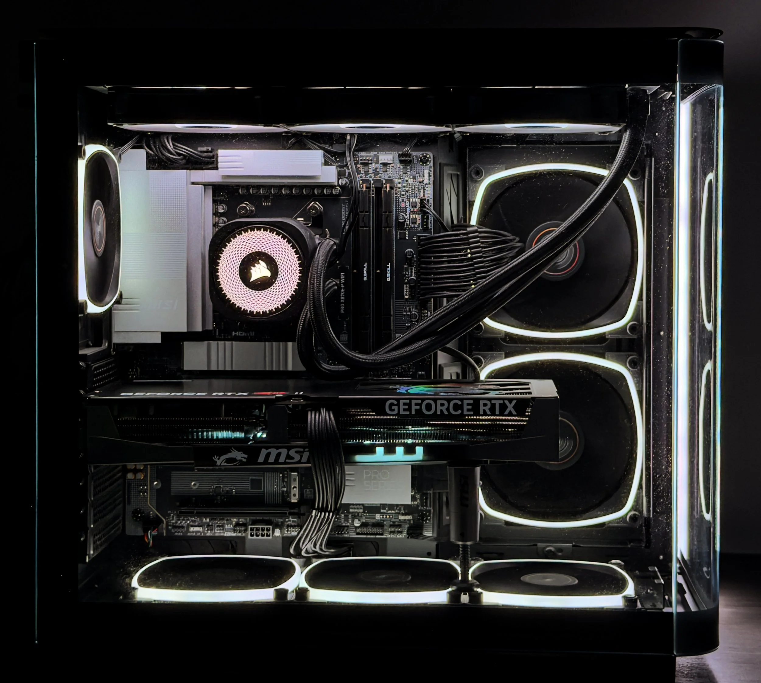 A custom-built gaming computer with transparent side panel displaying internal components, including cooling fans with white LED lighting, a graphics card, a CPU cooler, and various cables.