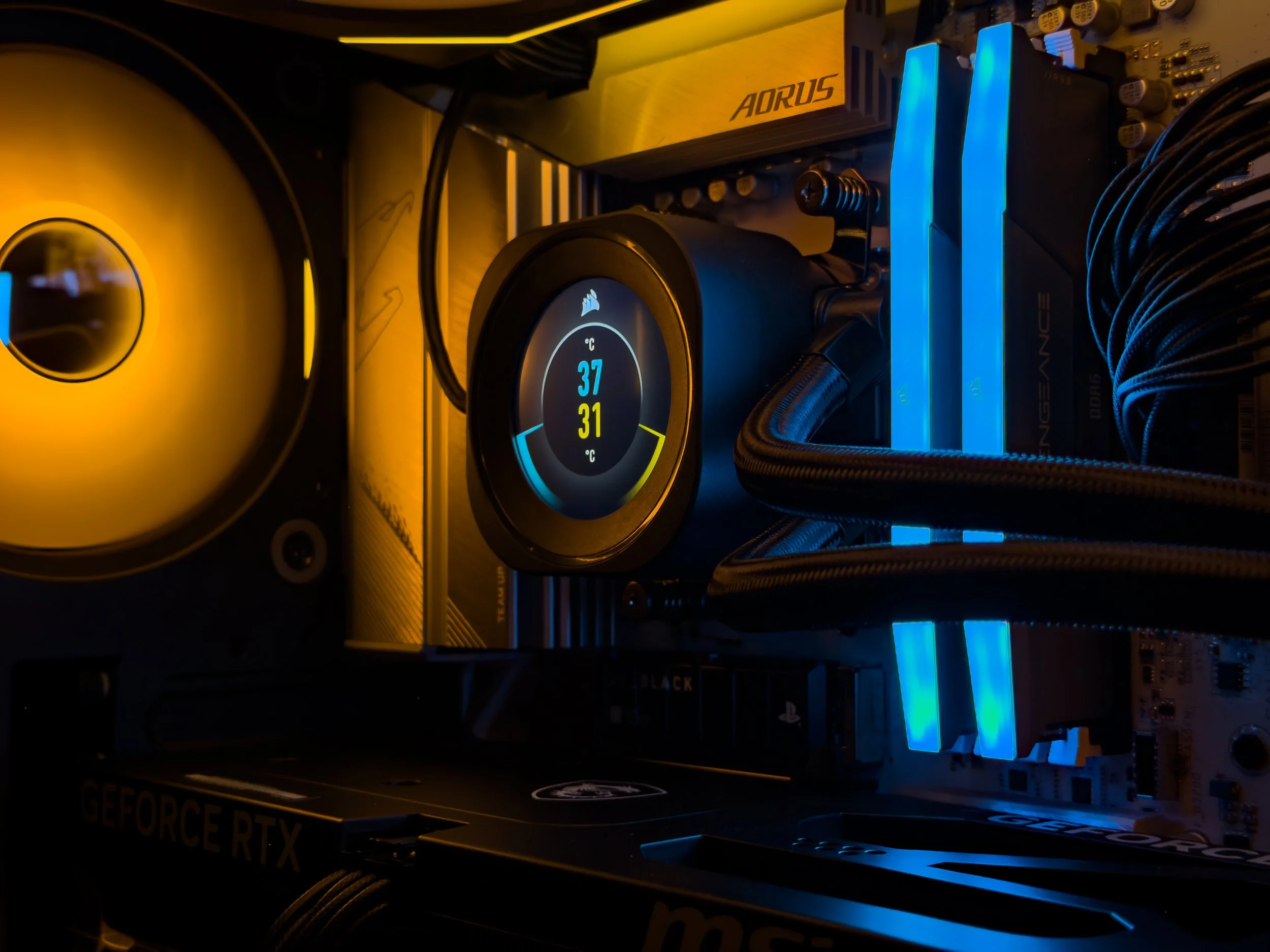 Close-up of a computer graphics card inside a PC, showing a digital display reading 37°C and 31°C, illuminated blue RAM sticks, and various internal components.