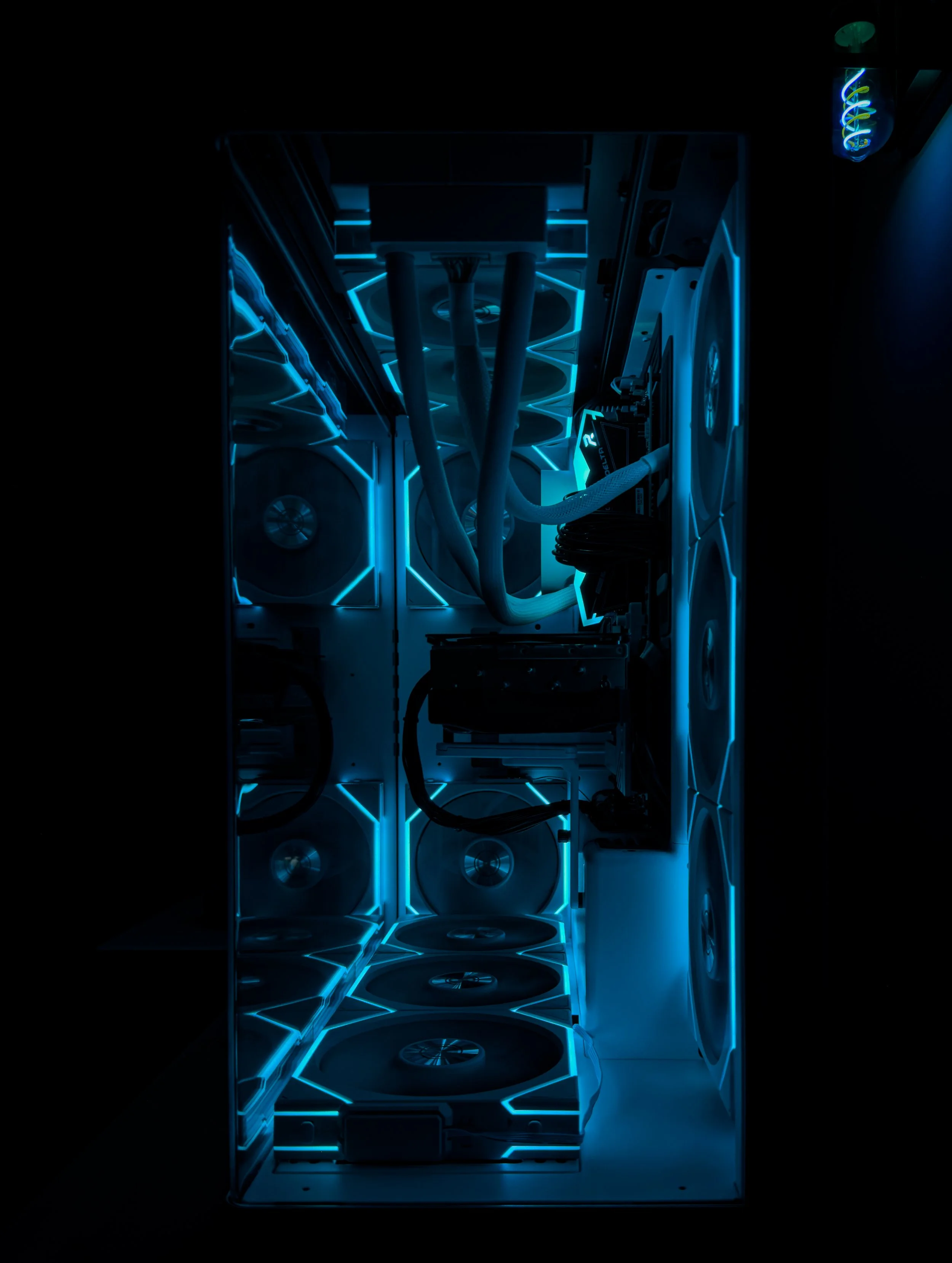 A computer mining rig with multiple fans, cooling tubes, and glowing blue LED lights inside a metal case.