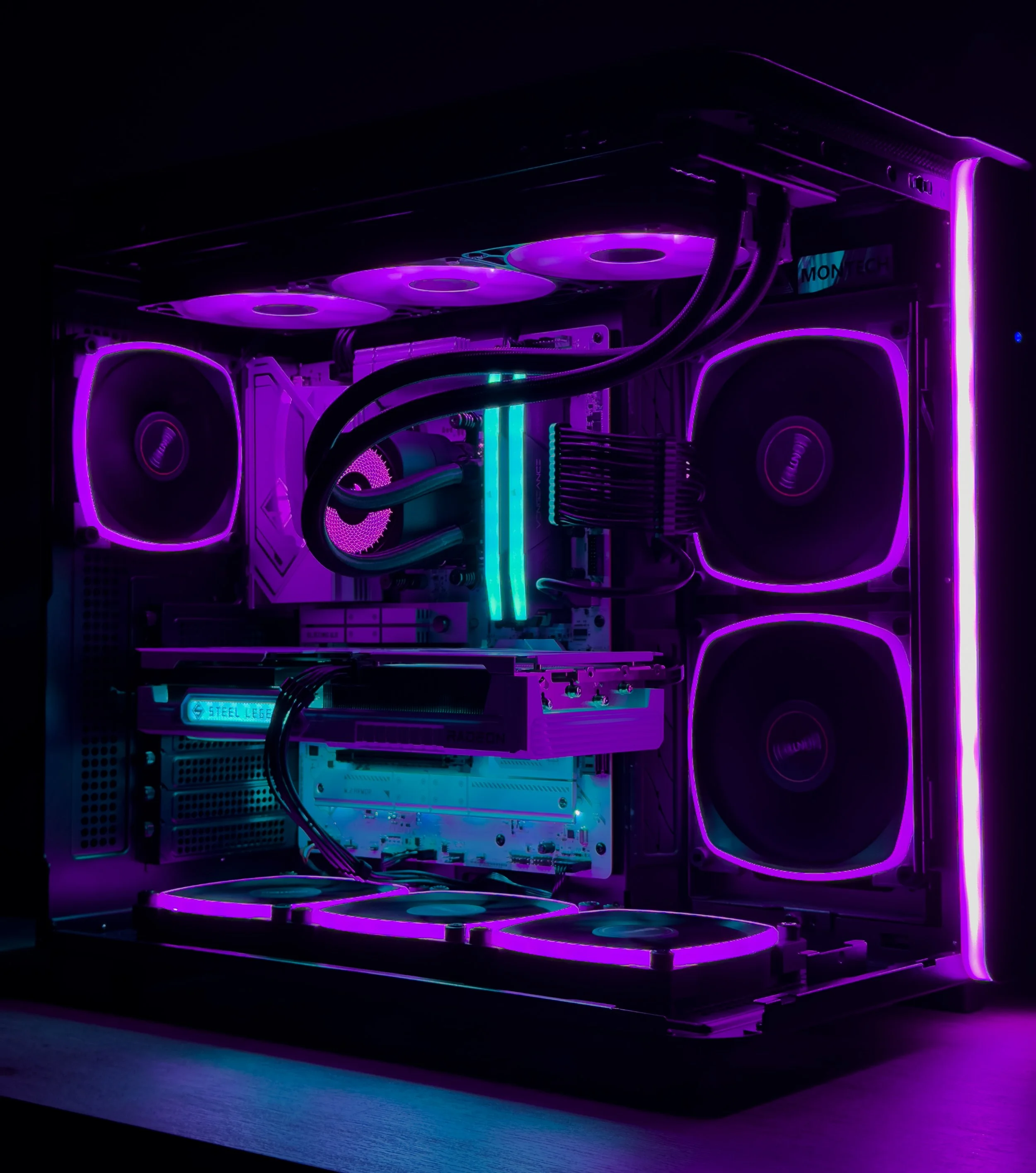 A custom-built gaming computer with a black case and purple neon lighting, featuring large cooling fans, liquid cooling tubes, and RGB components inside.