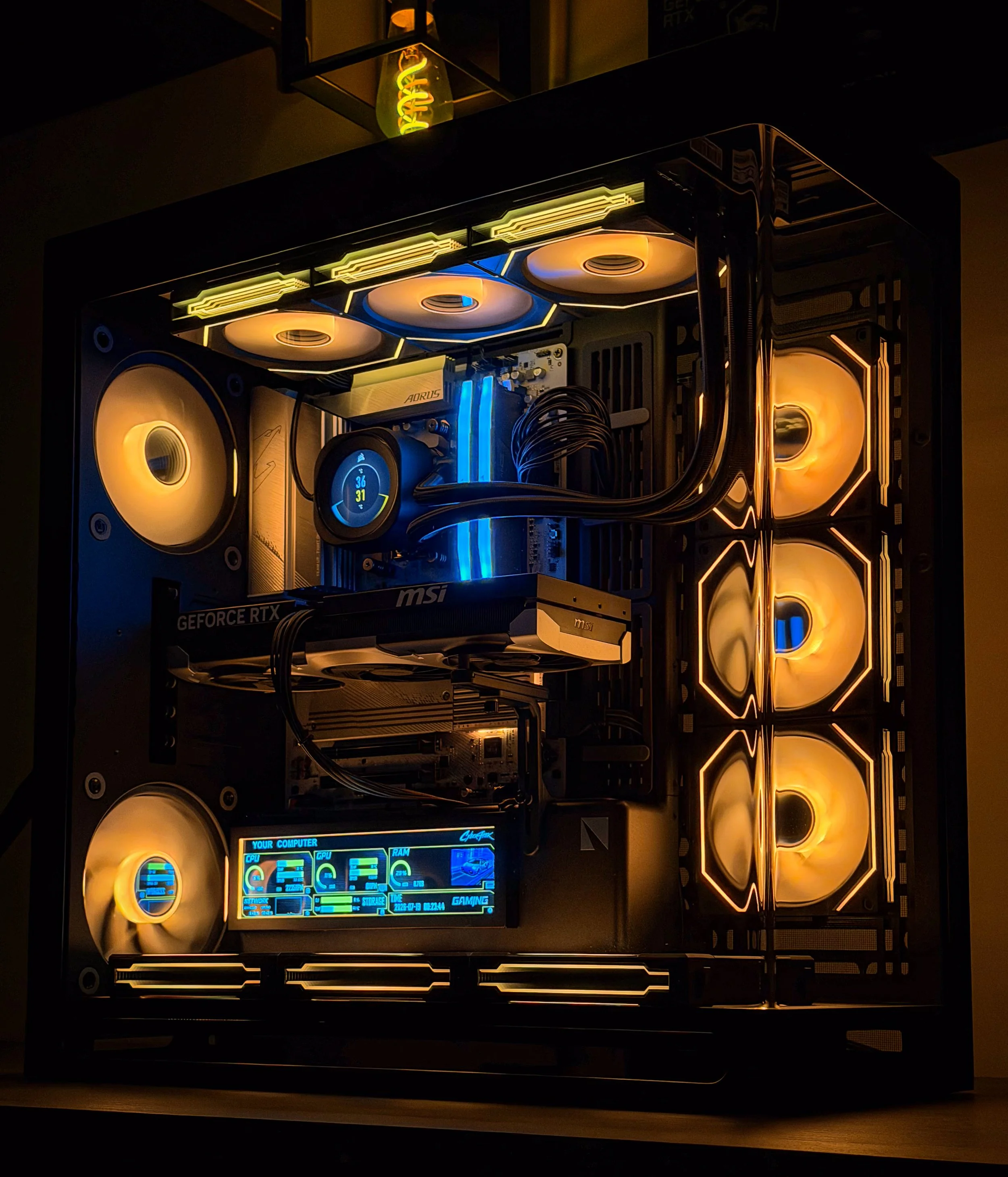 Close-up of a custom gaming computer with illuminated fans, a digital monitor, and internal components visible with blue and yellow lighting.