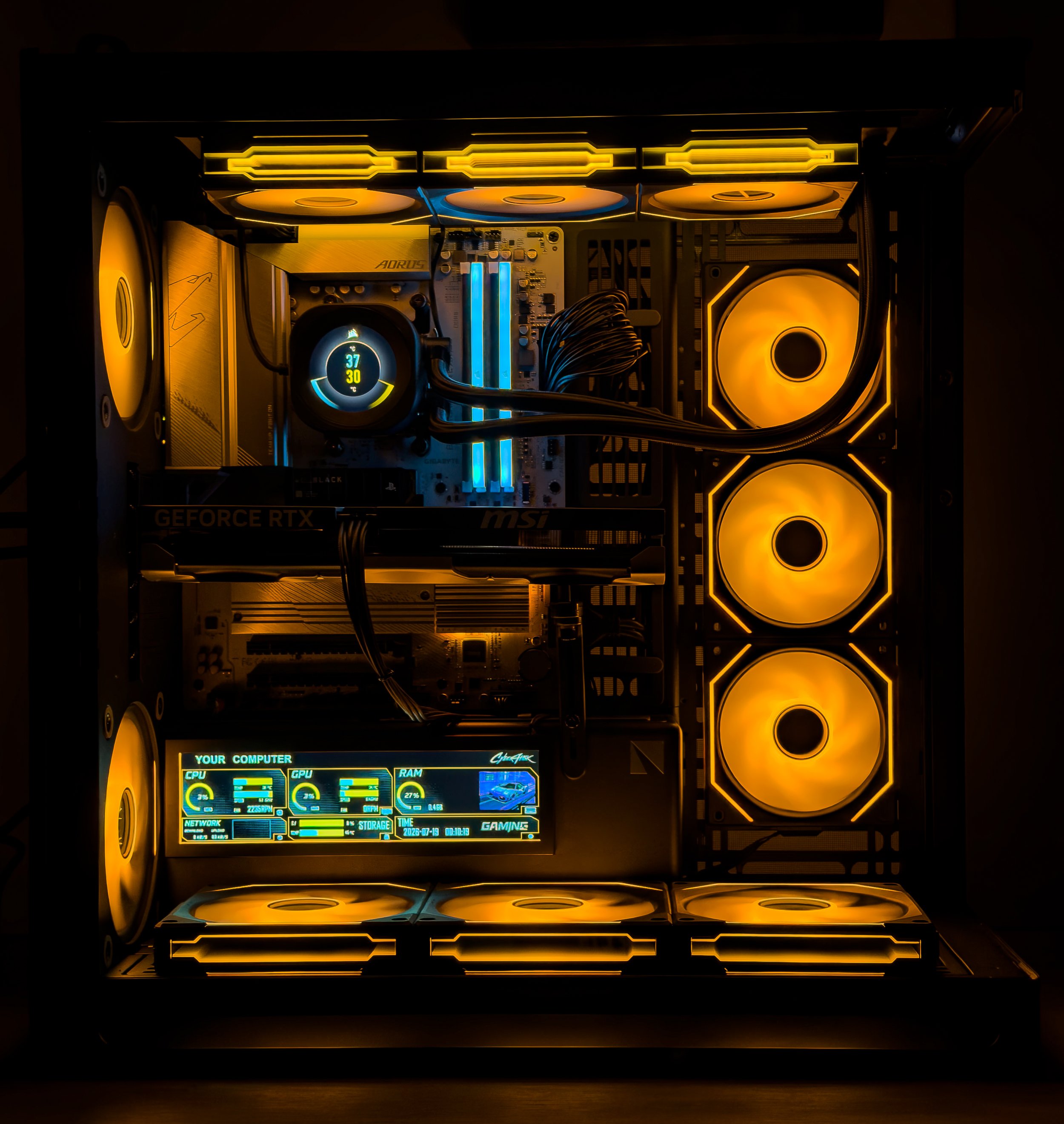 Close-up of a custom gaming computer interior with illuminated yellow and blue LED lights. The components include a large yellow cooling fan, a motherboard with RGB lighting, and a liquid cooling system with a display showing system stats such as CPU