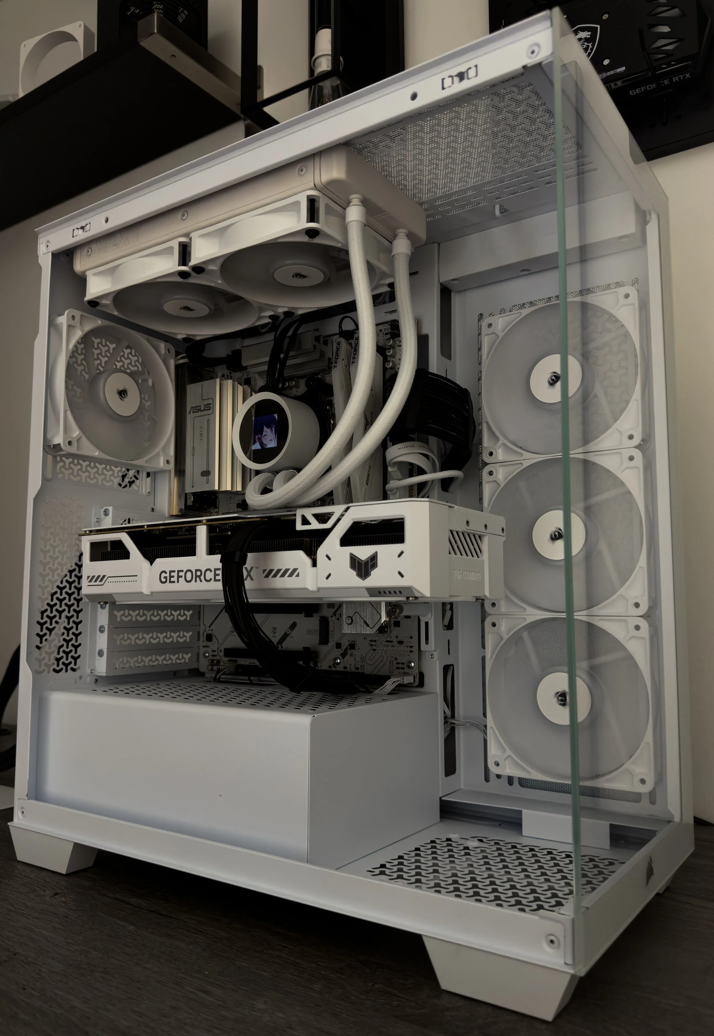White custom-built computer case with visible internal components, including cooling fans, liquid cooling system, and a graphics card, placed on a dark wooden surface.