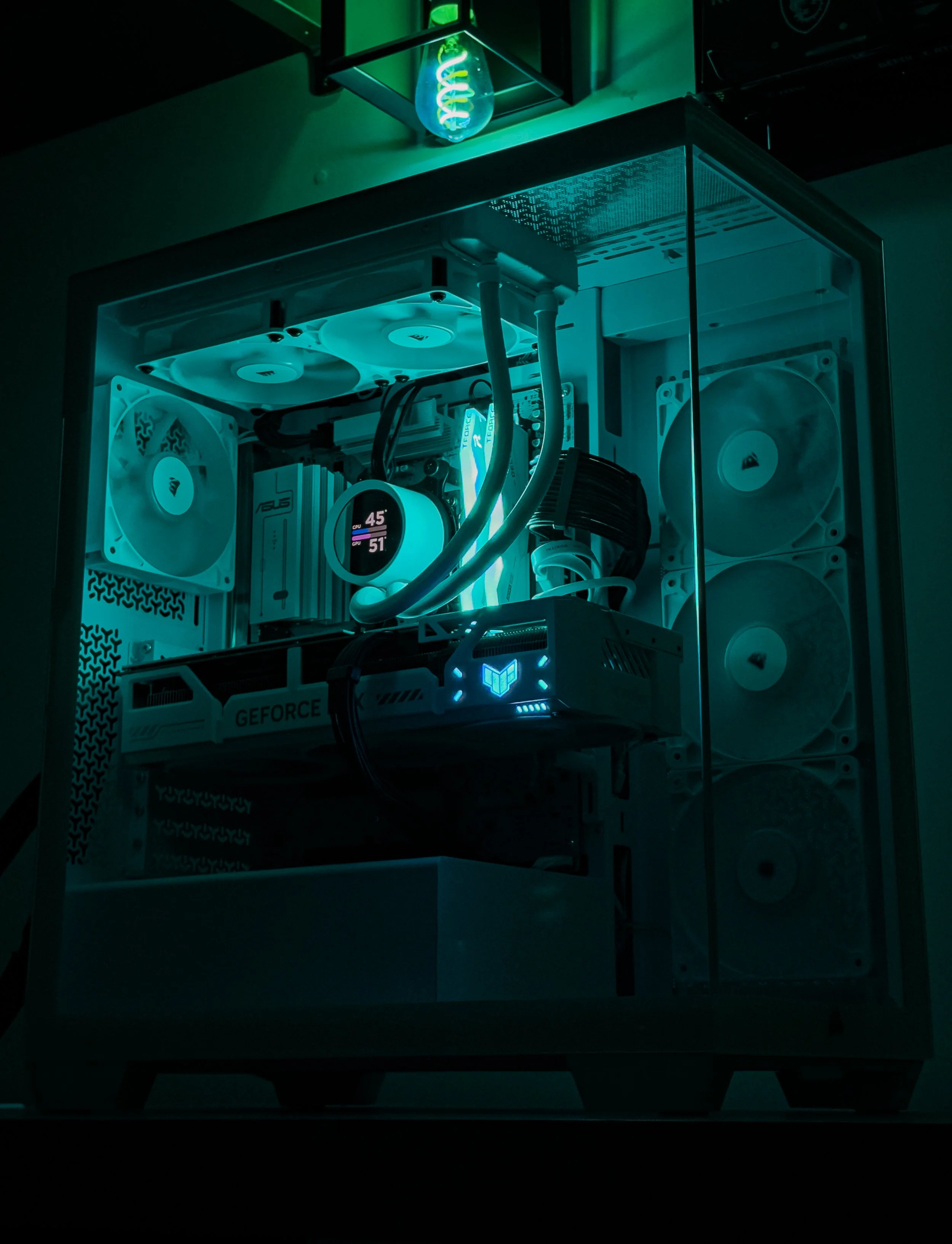 A gaming computer setup with illuminated cooling fans and a neon snake light lamp on top, inside a case with a glass side panel.