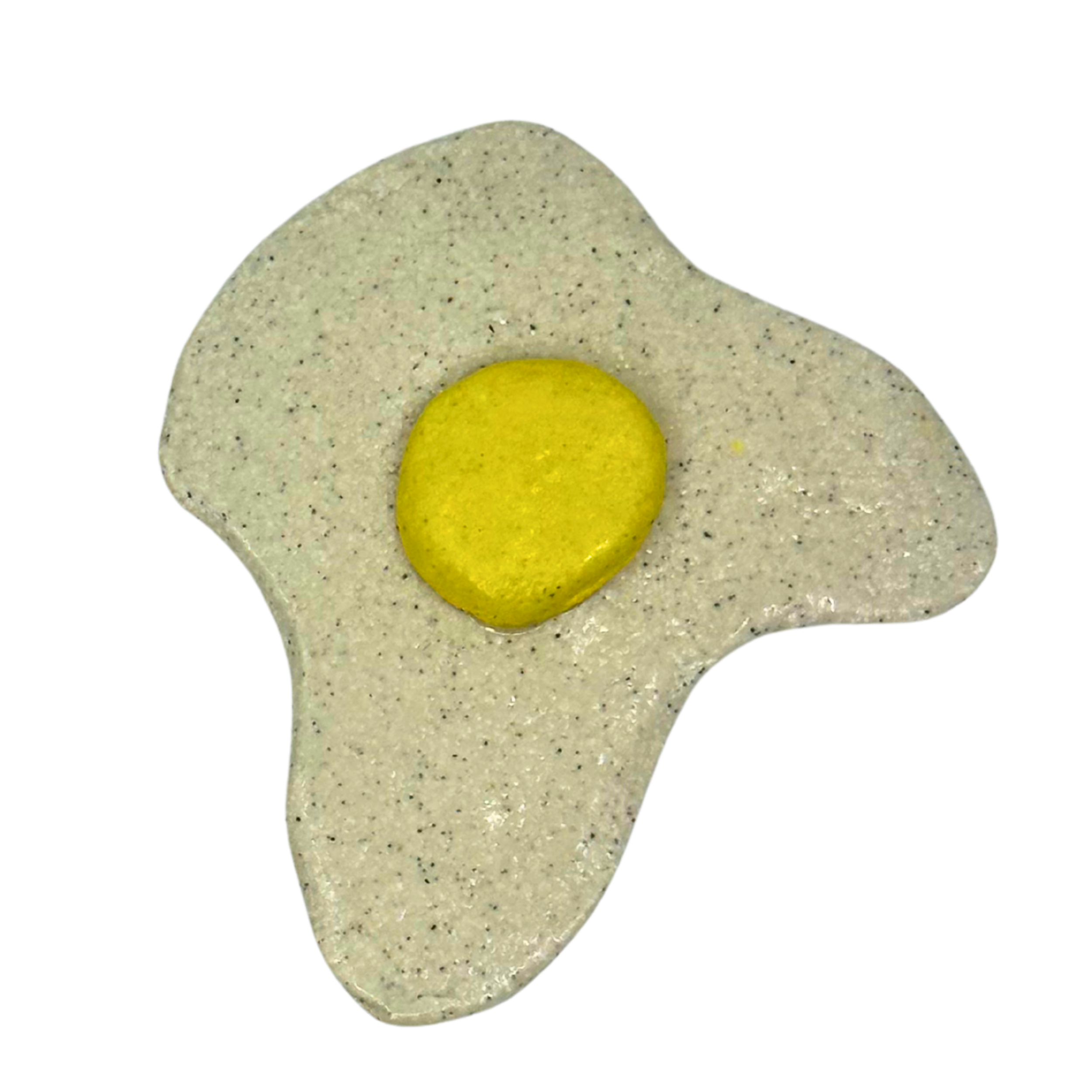 Close-up of a fried egg with a bright yellow yolk, on a speckled beige surface.