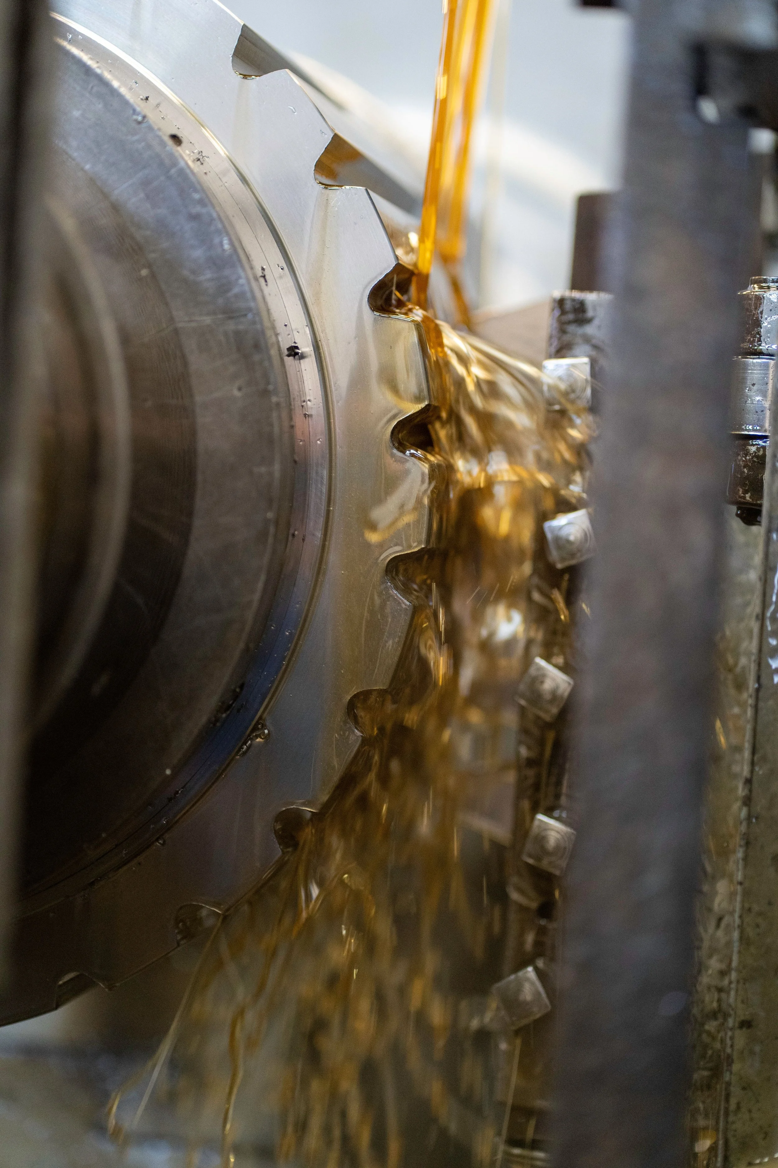 Close-up of gears with lubricant or oil dripping from them, part of a machine or mechanical system.
