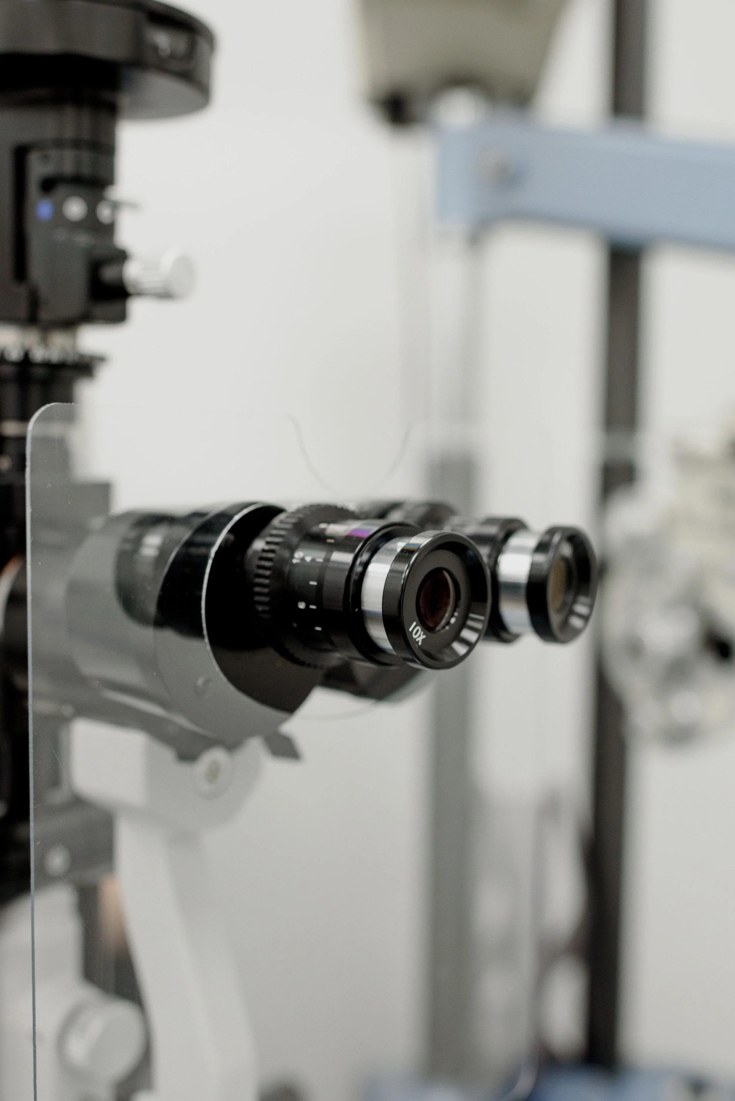 Close-up of a microscope focusing on its objective lenses and part of the stand.