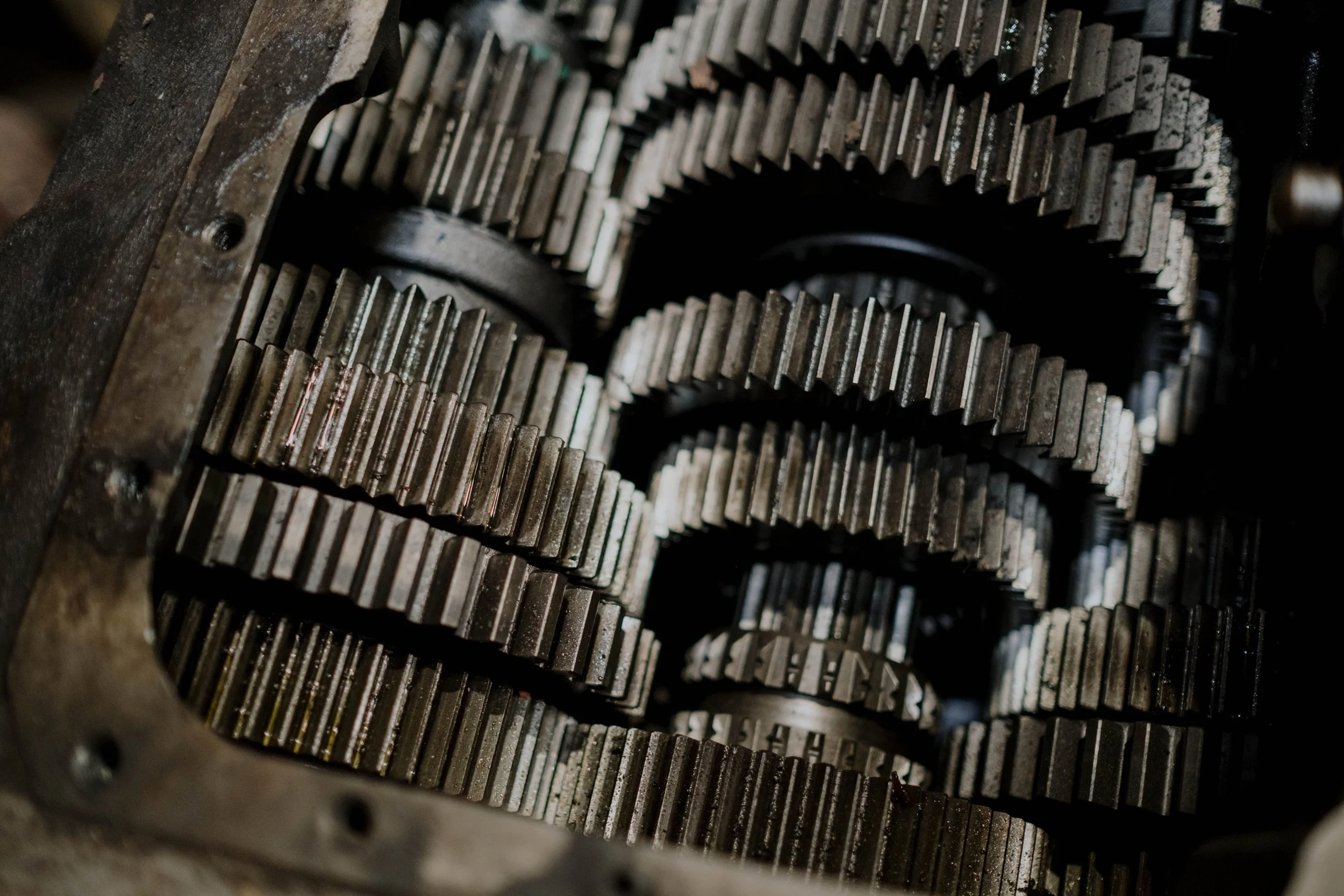 Close-up of multiple metal gears with worn teeth, arranged in a complex mechanical structure.