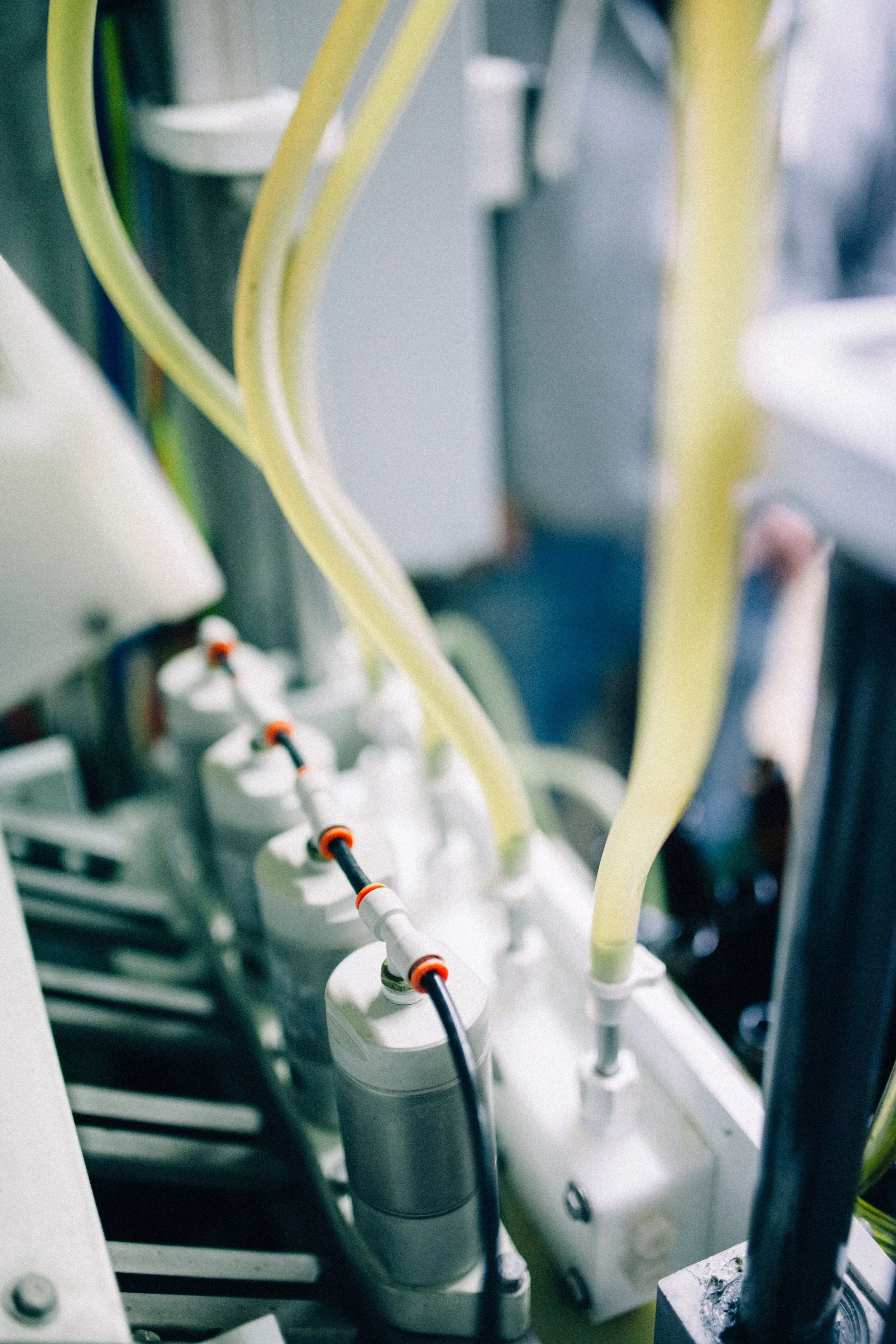 Close-up of laboratory equipment with multiple white and black electrical connectors, yellow and black tubes, and metallic components.