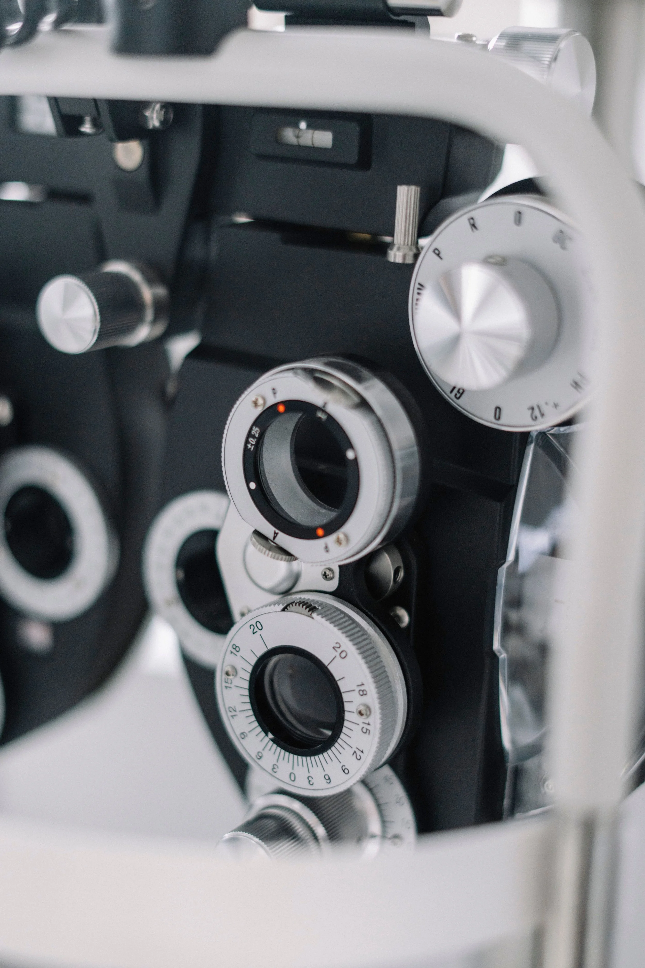 Close-up of a slit lamp used in optometry with focus on the adjustment dials and mechanisms.