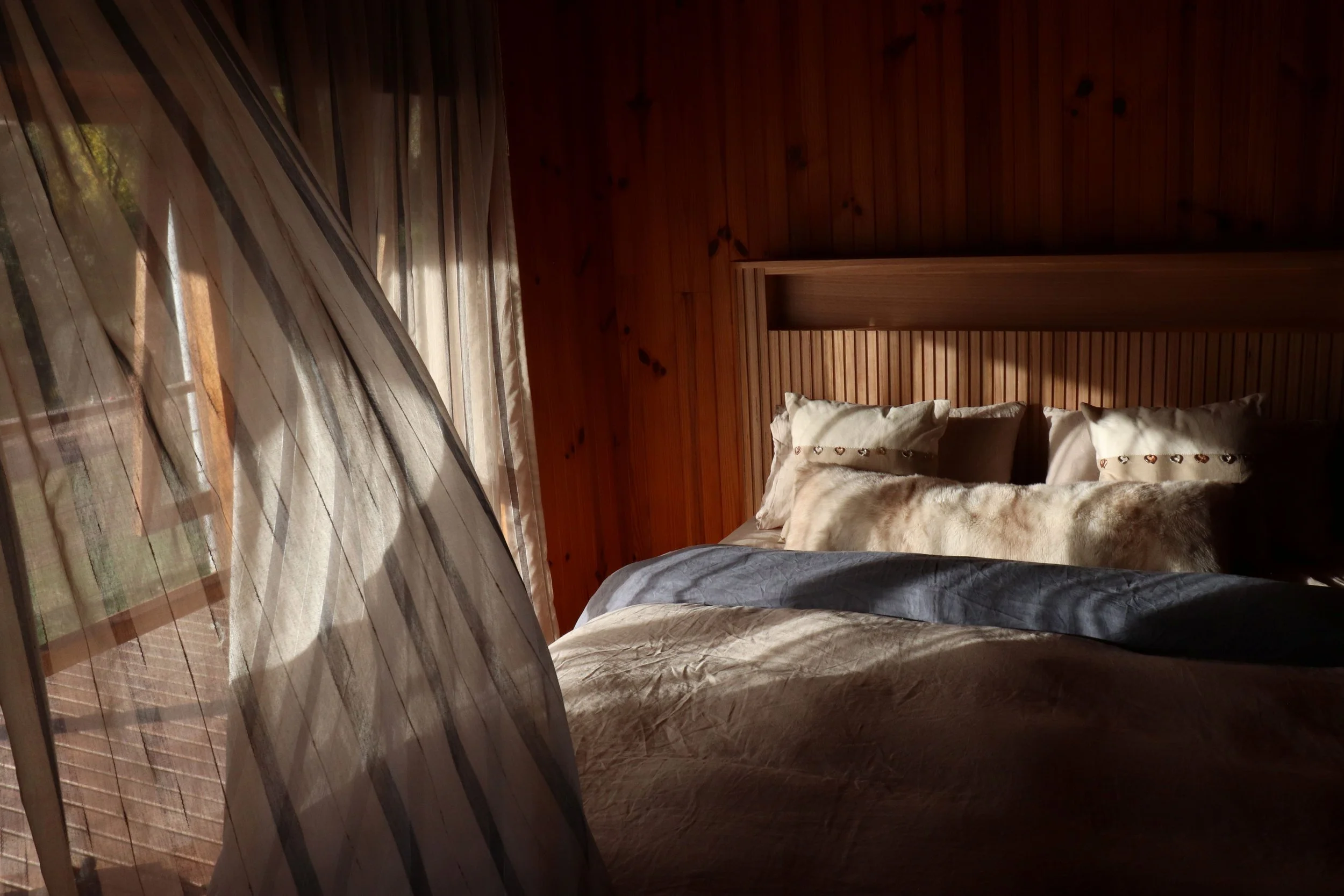 Queen size bed with natural fibre linens and built in headboard light in Howqua, Victoria
