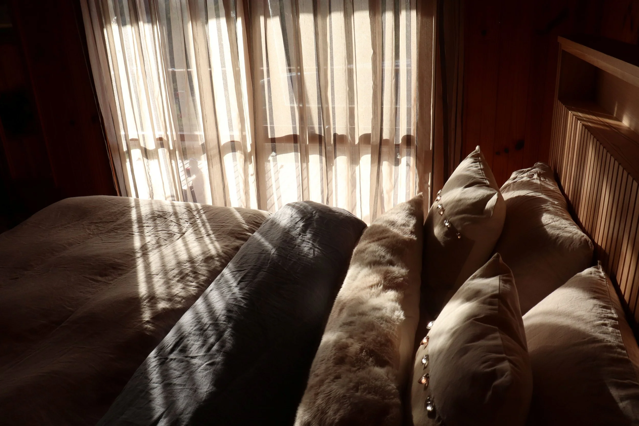Romantic Queen size bed with natural fibre bedding and sheer curtains for privacy in Howqua Valley for short term stays