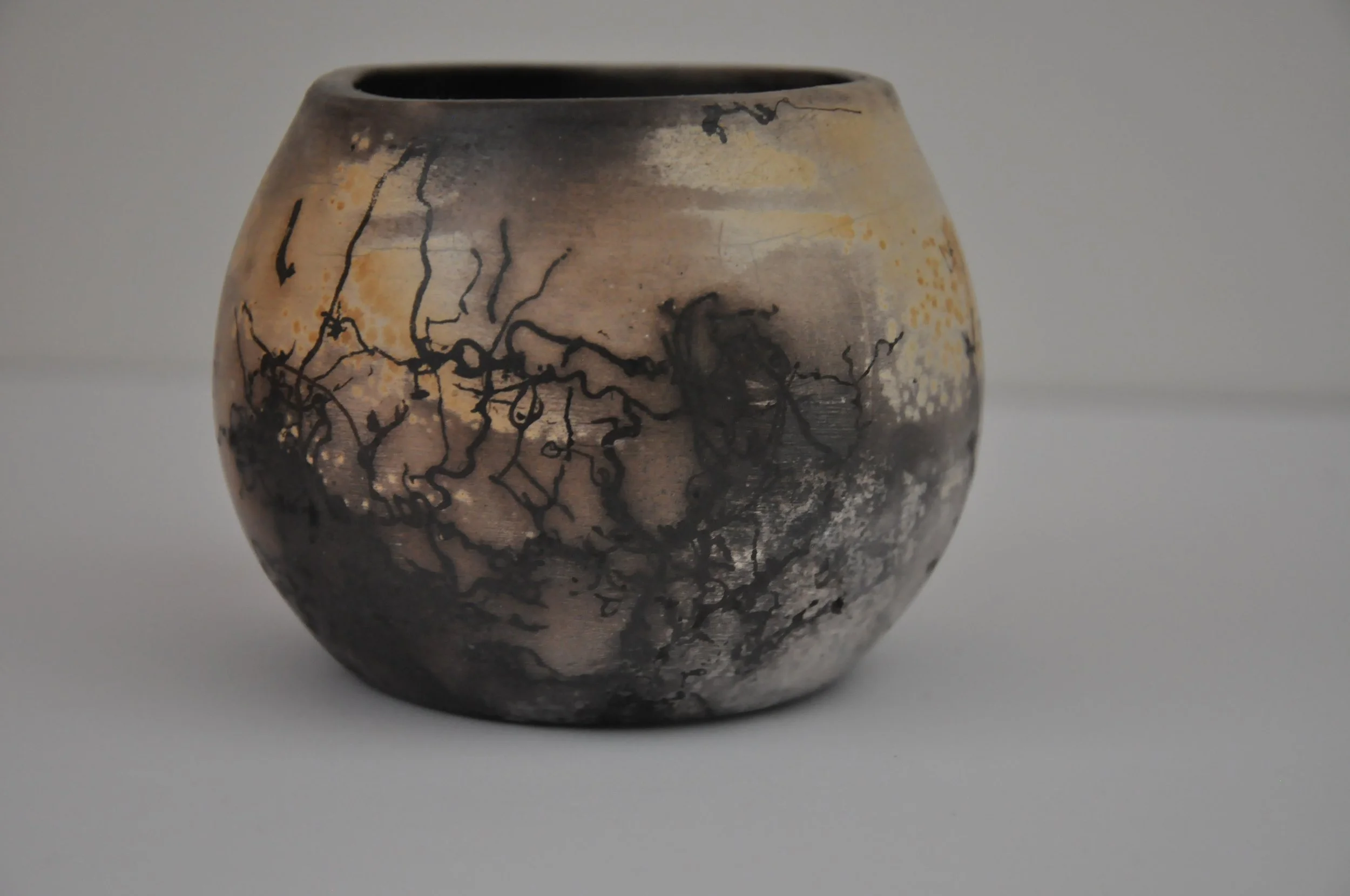 Vase en céramique avec un motif de lignes noires et dégradés de couleur beige, gris et noir.