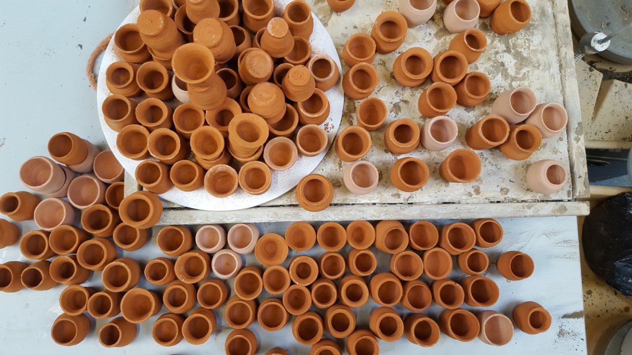 Bakstenen en kleipotten in verschillende stadia op een werktafel.
