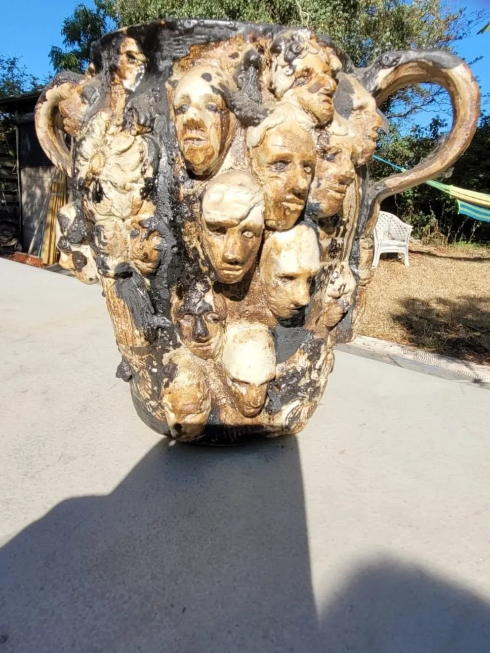 Een bakje gemaakt van hout met honderden gezichten met verschillende uitdrukkingen en kenmerken, gecombineerd in één kunstwerk.