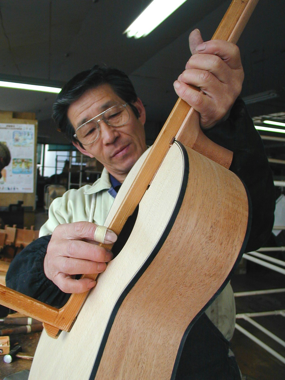 Un artisan K Yairi travaille sur l'assemblage du manche en queue d’aronde pour une guitare acoustique