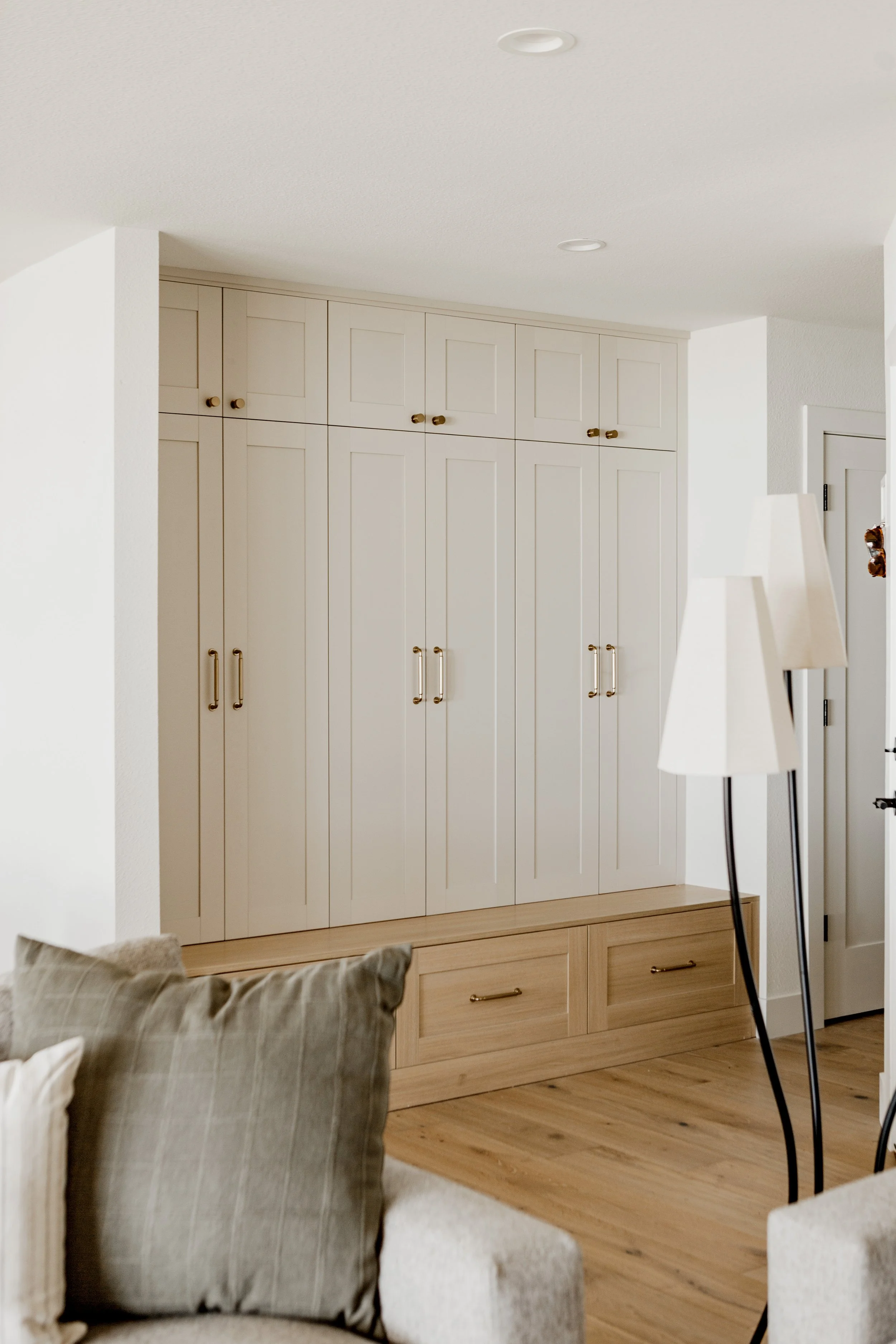 Living room with beige couches, a lamp, and a built-in white cabinet with gold handles in the background.