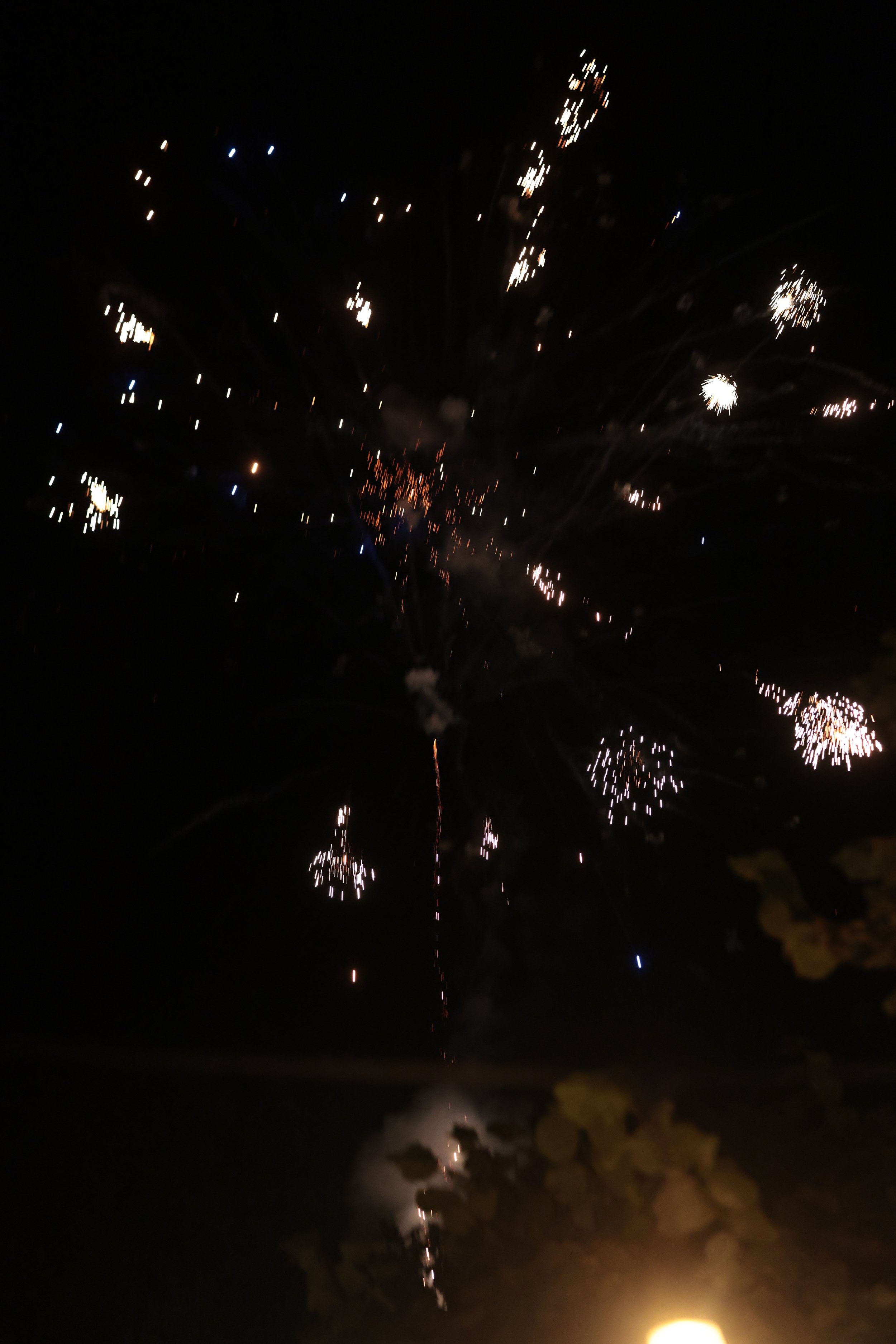 Fireworks exploding in the night sky with bright streaks and sparkles.