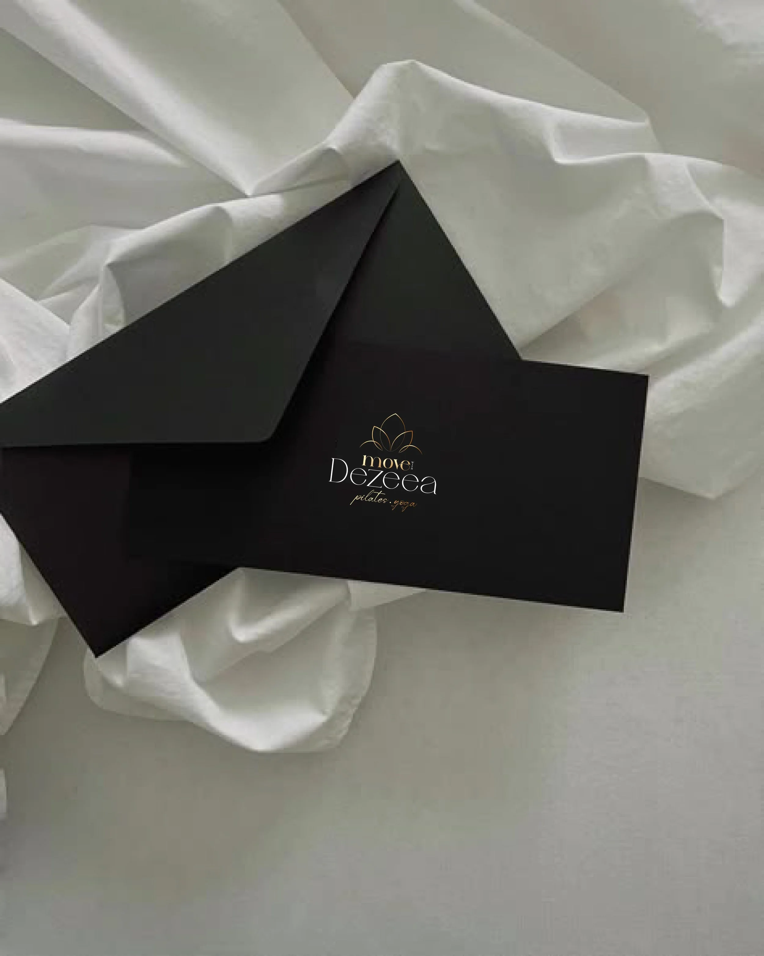 Close-up of a black box with the logo and text 'move Dezeea pilates yoga' on it, resting on crumpled white tissue paper.