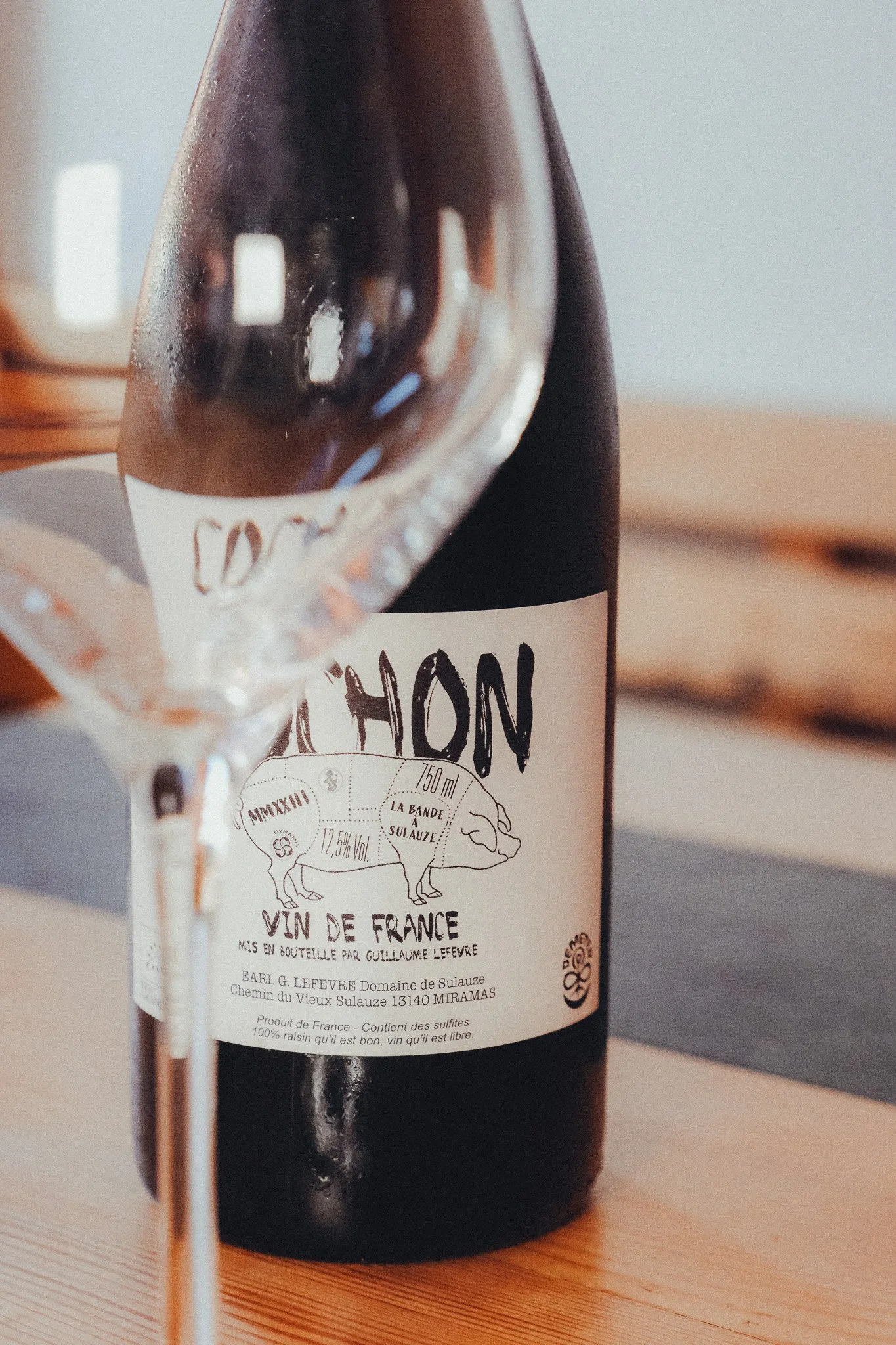 Bottle of French wine with a detailed label, sitting on a wooden surface.