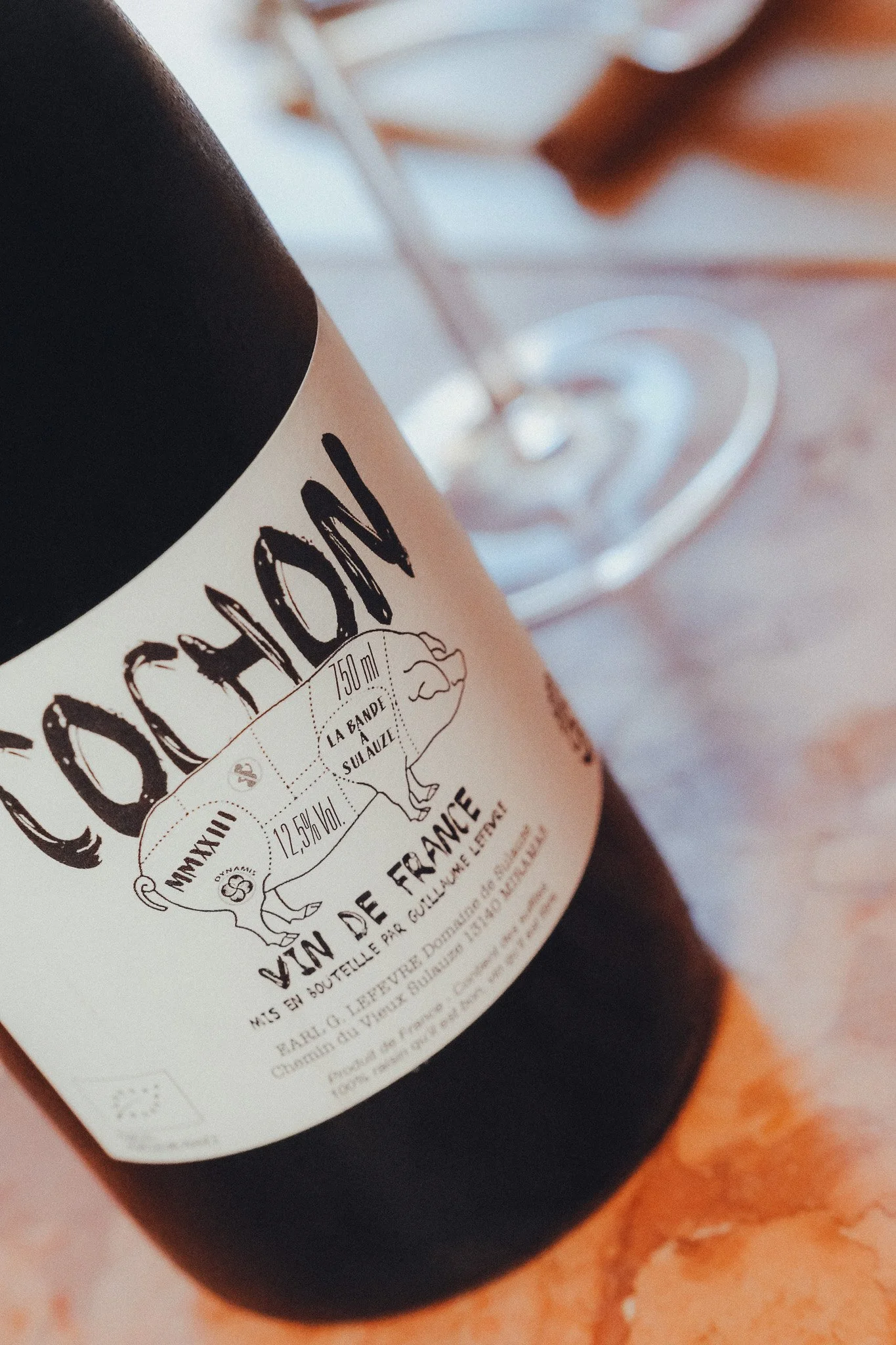 Close-up of a wine bottle with a detailed label, set on a warm-toned surface.
