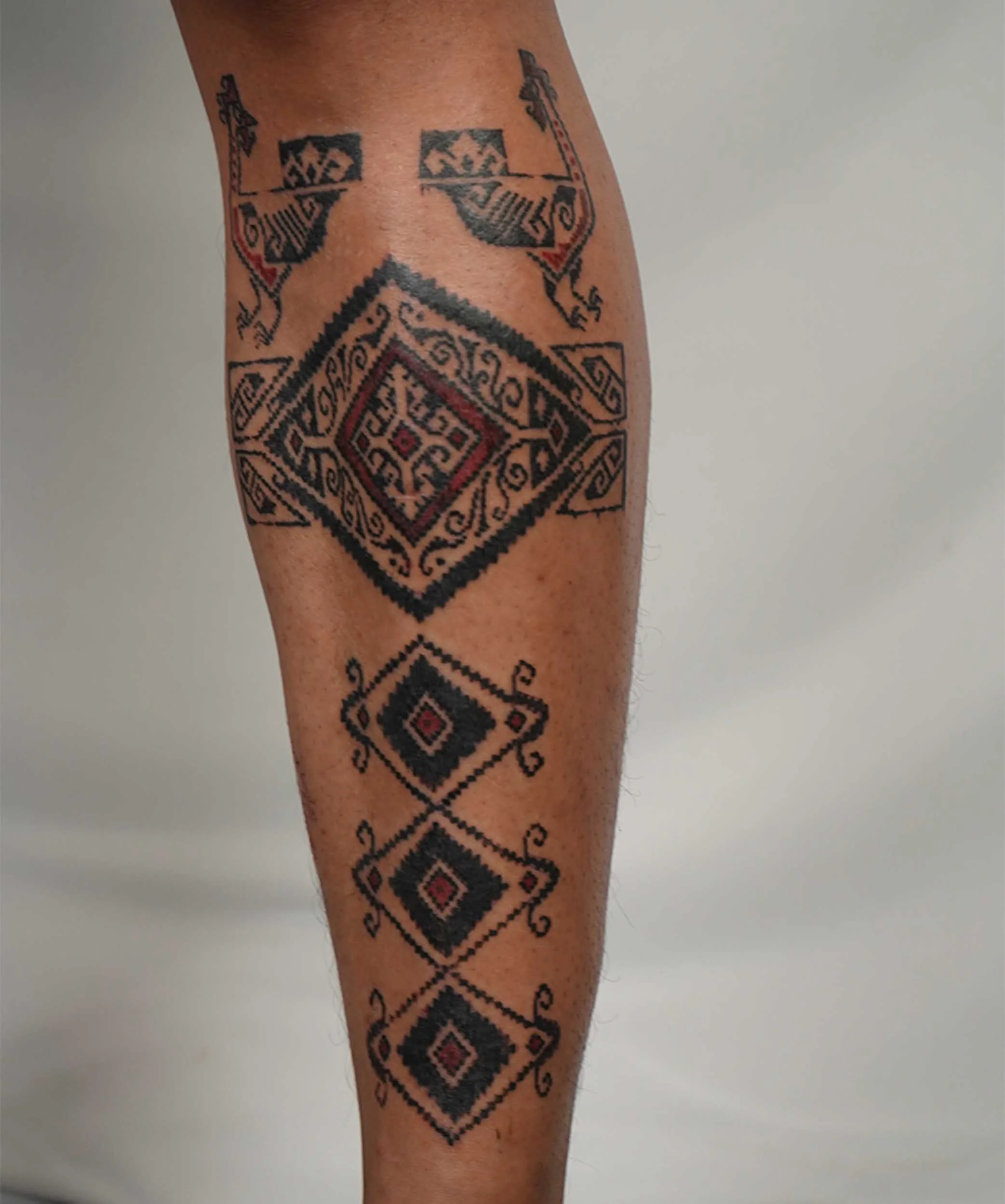 close up picture of man shin with ornamental tattoo inspired by tenun gringsing and batik pattern by bali based artist