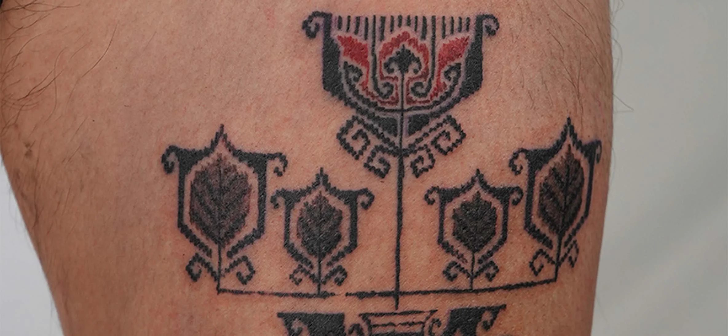Tattoo in black ink with geometric and floral patterns on a person's skin.