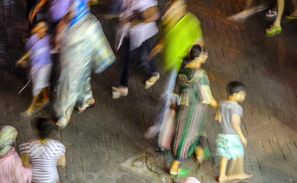 Photographie abstraite — mère et enfant en mouvement, saris colorés, pavés de Jemaa el-Fna Marrakech la nuit | Bybadr