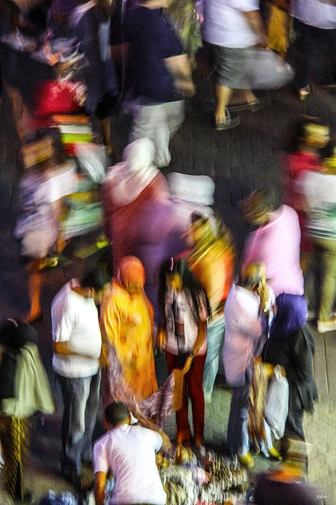 Photographie abstraite vue plongeante — foule colorée place Jemaa el-Fna Marrakech la nuit, saris et couleurs vives | Bybadr

