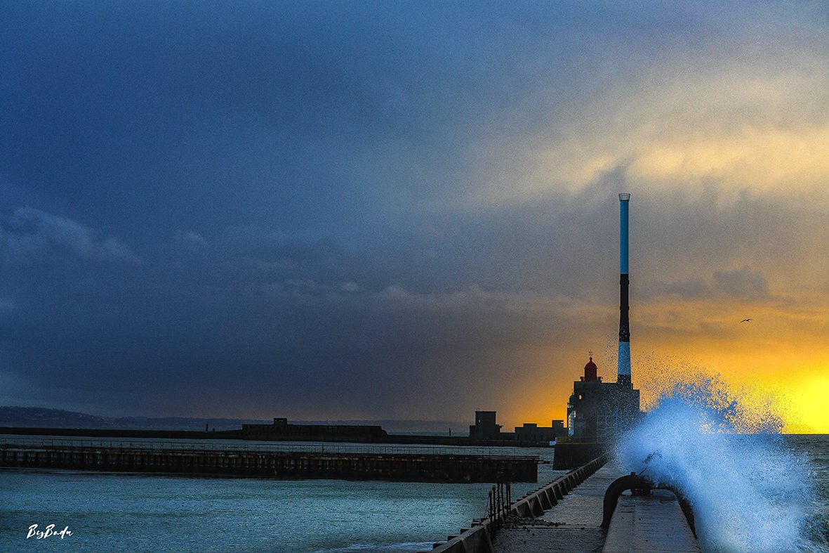 Phare + vague bleue + coucher bleu et or — superbe clôture !
`Le bleu et l'or. La vague et le phare. La Manche choisit ses couleurs — et elle choisit bien.`