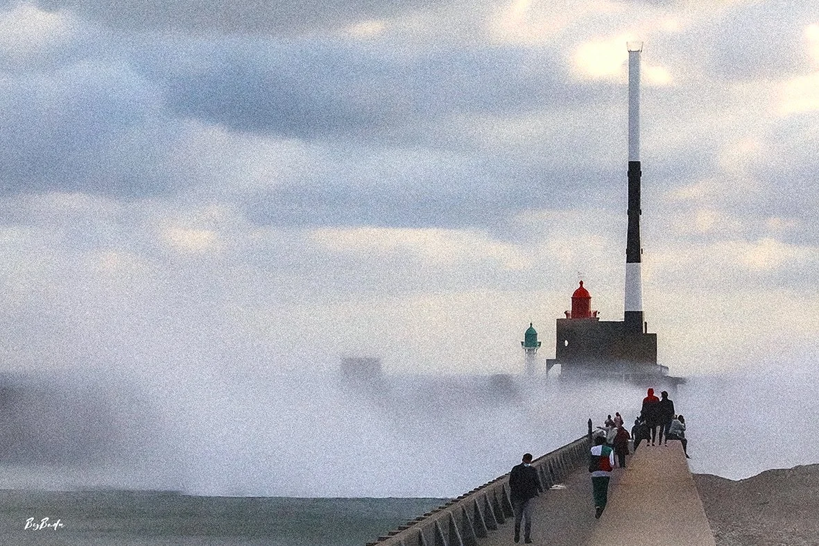 La jetée sous l'assaut. Le phare tient. Les hommes aussi.
La Manche — jetée sous la brume des vagues, phare et foule normande | Bybadr