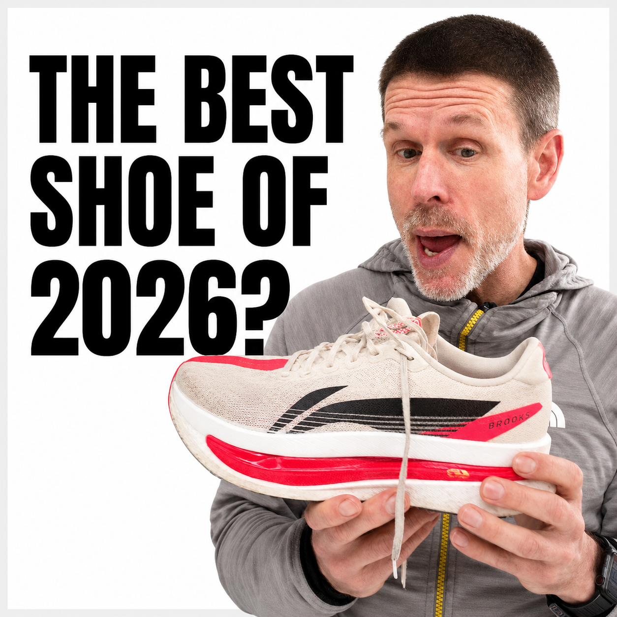 A man in a gray jacket holding a white and red Brooks running shoe with black accents, looking at it with surprise. There is bold text to the left that reads 'The Best Shoe of 2026?' on a white background.